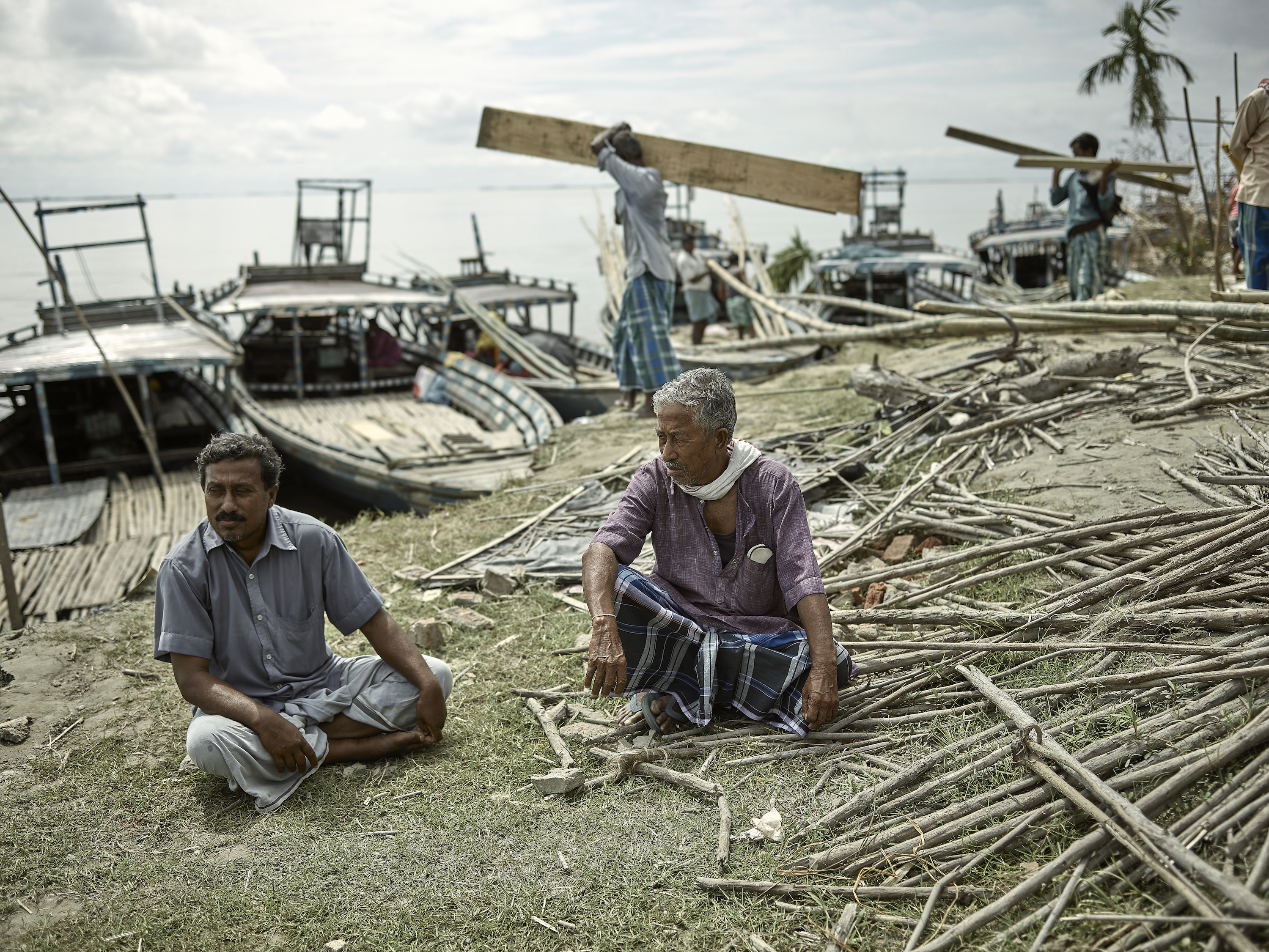 Moinul and Haidar Ali sit on the riverbank of Bhangnamari Char as the bamboo wreckage of their local school, built in 1948, is loaded onto ships for sale in the mainland. The school was destroyed during intense flooding in July.