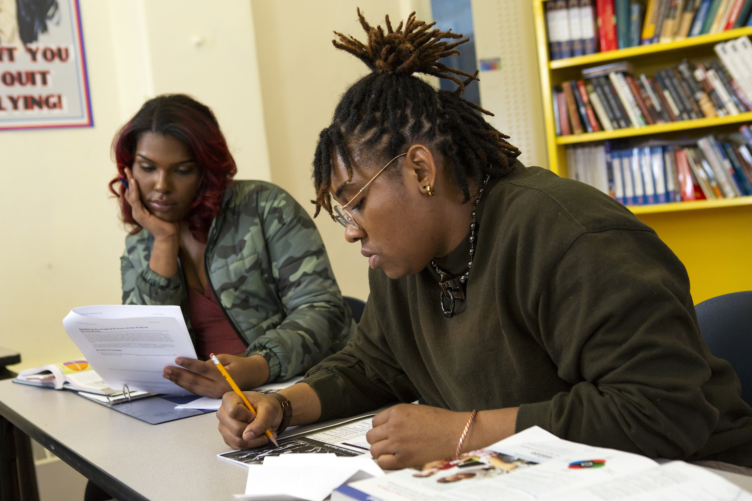 A non-binary student taking notes in class
