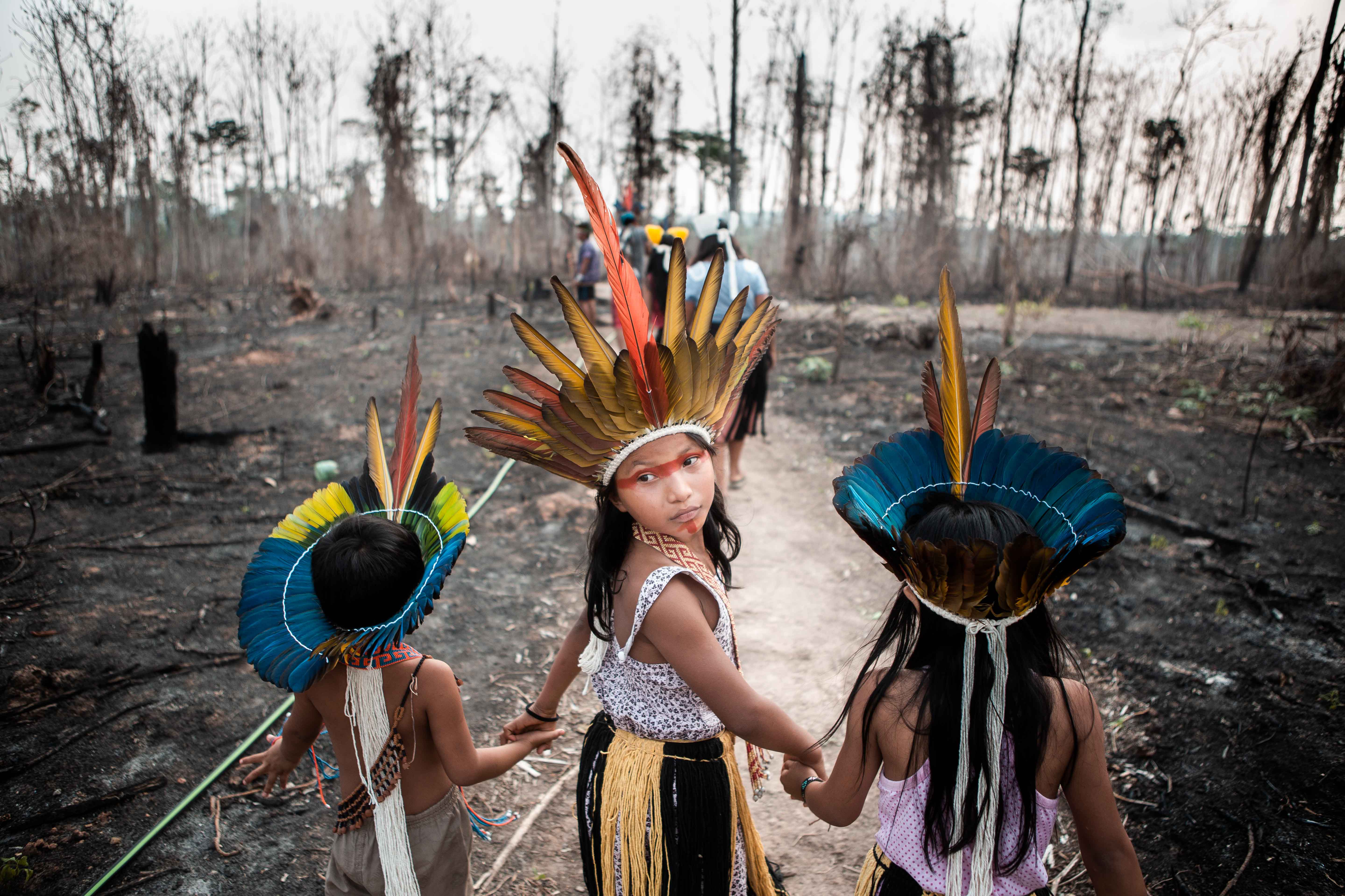 Three little indigenous girls walking on burnt land