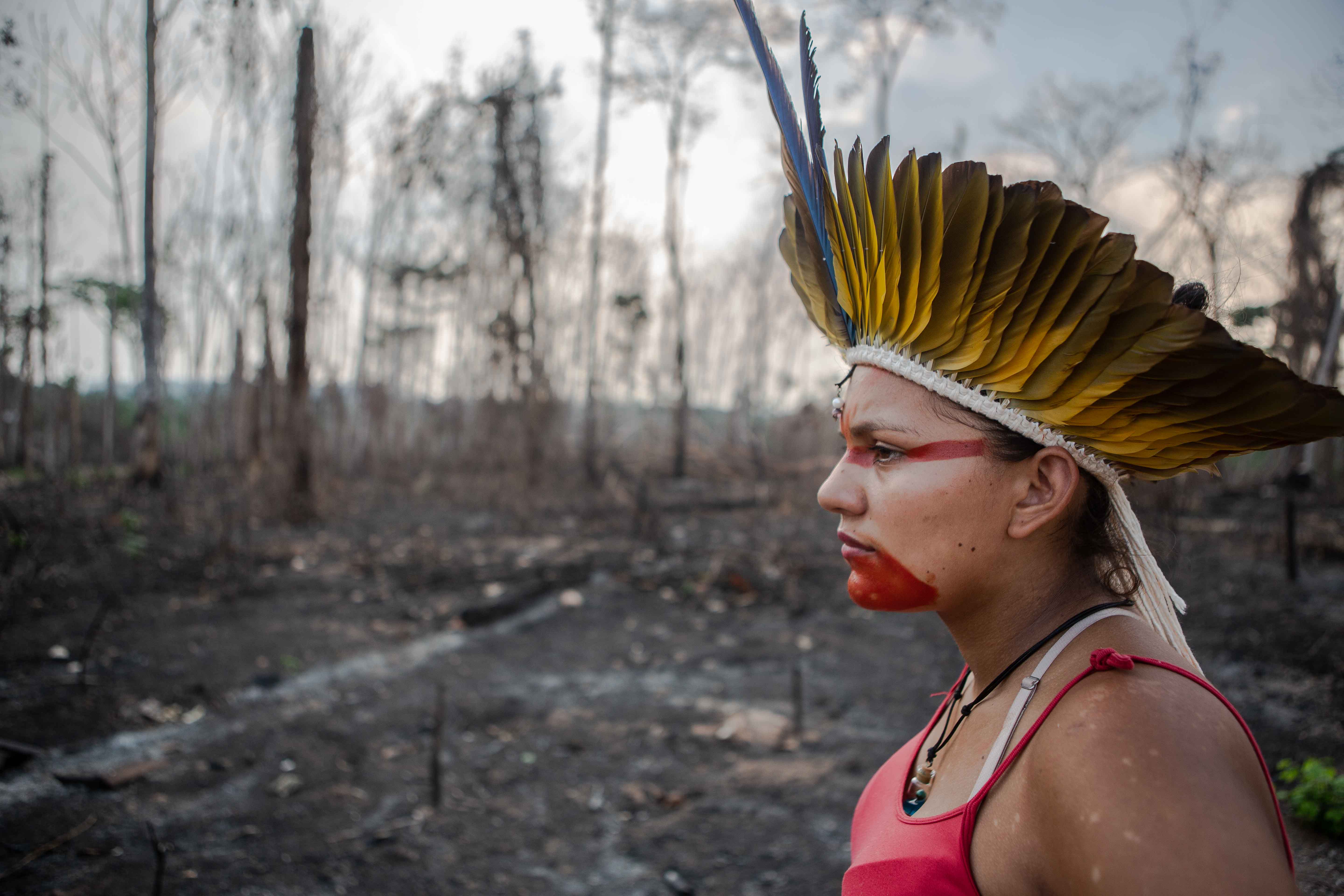 Indigenous woman in front of burnt land