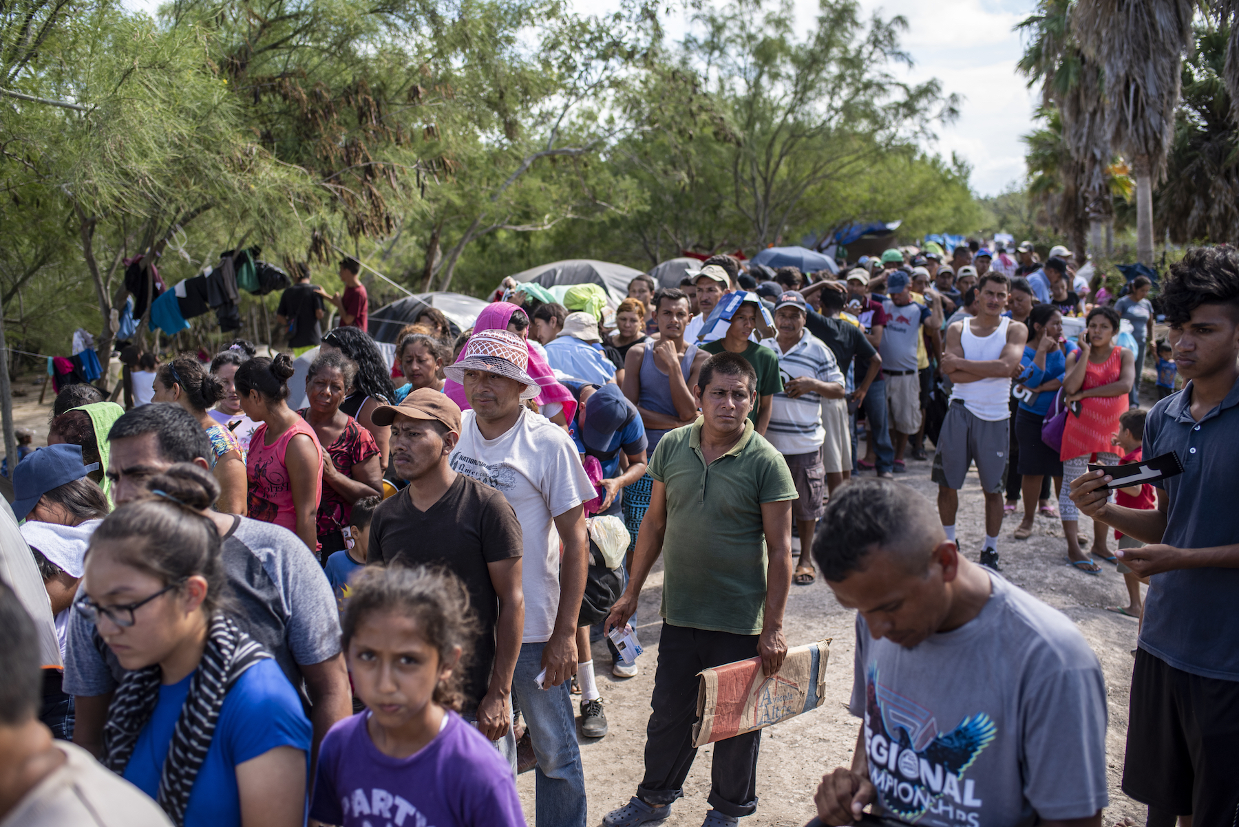 Migrants line up to receive donations of food and clothing. Photo by Sergio Flores.