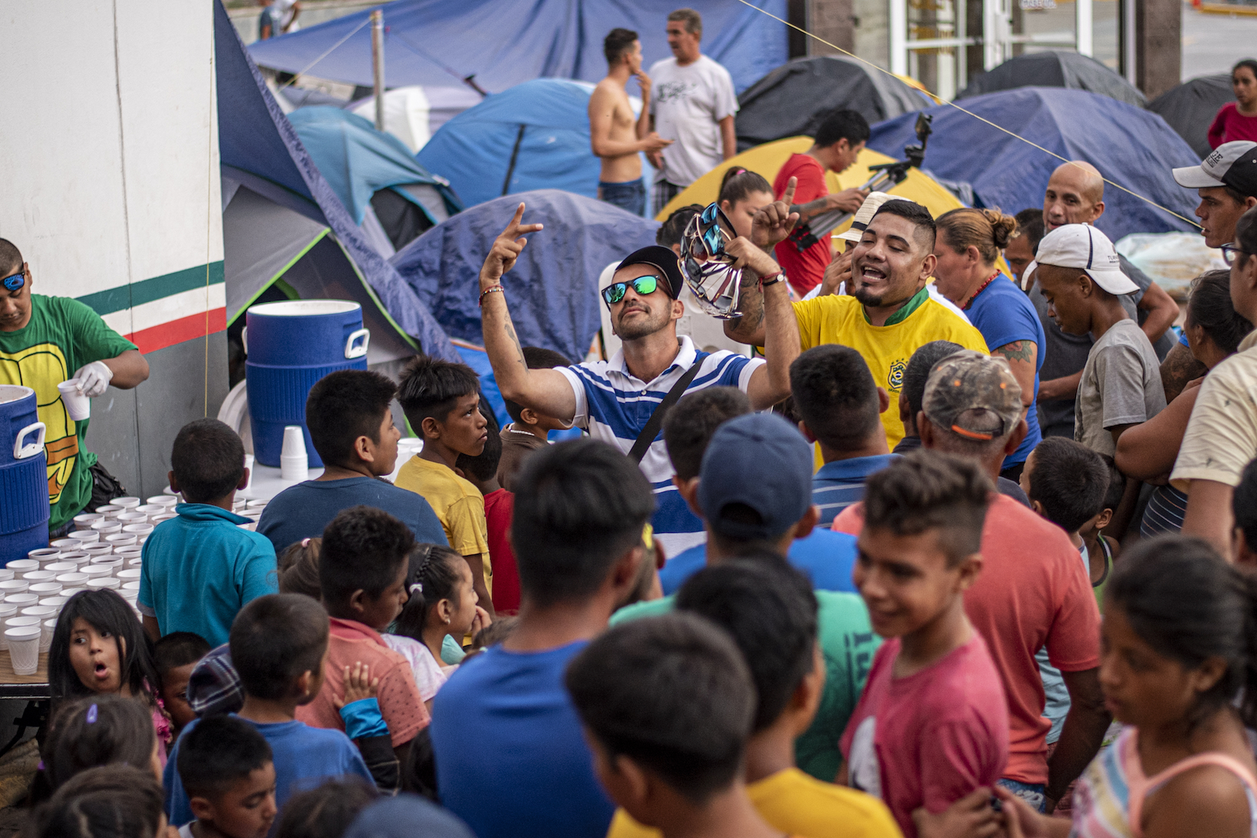 Volunteers from Mateo 25:35 rap while migrants wait in line for food. Photo by Sergio Flores.