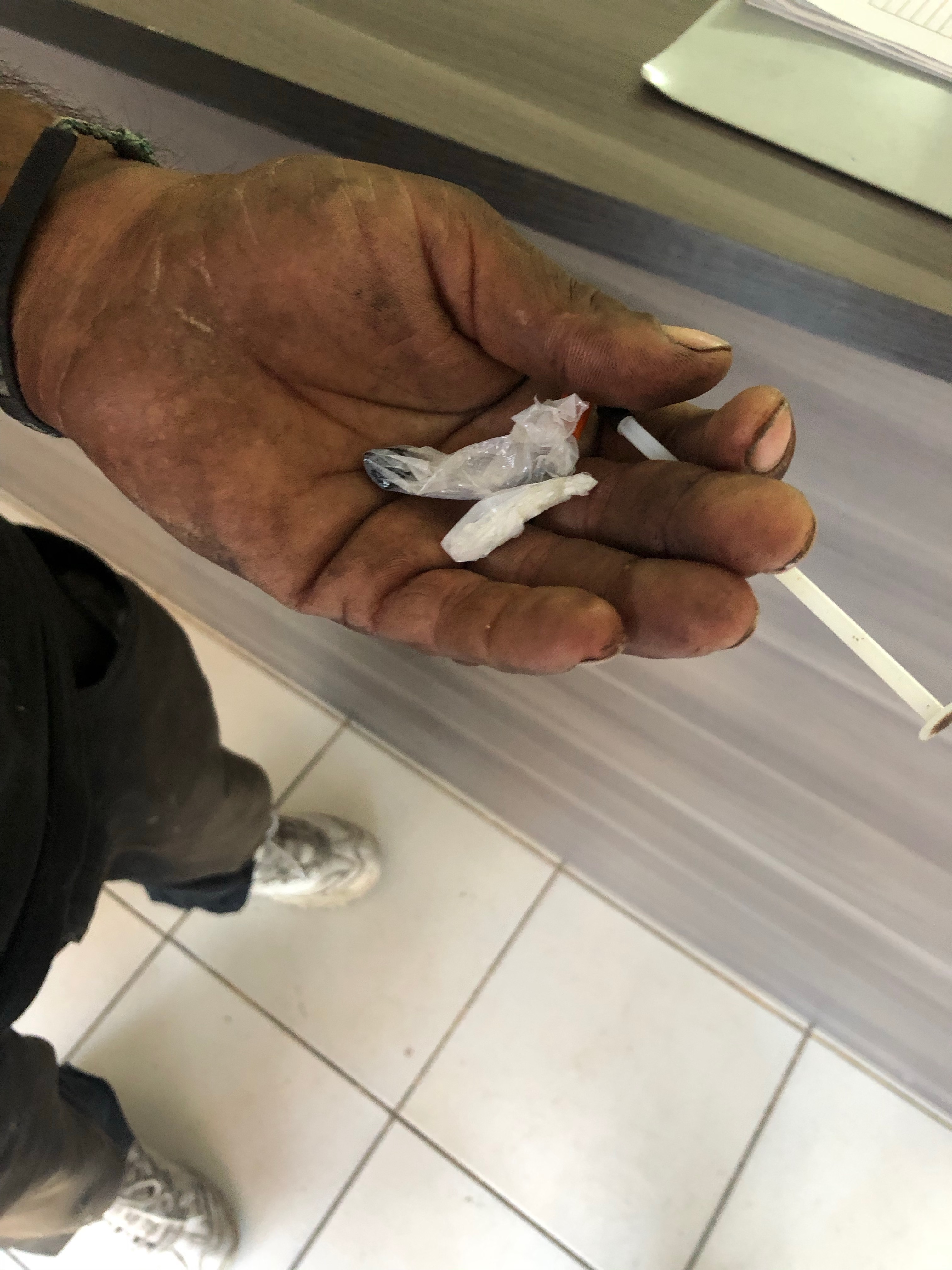 A heroin user shows in their hand a combination of white powders, meth and heroin, in plastic baggies.