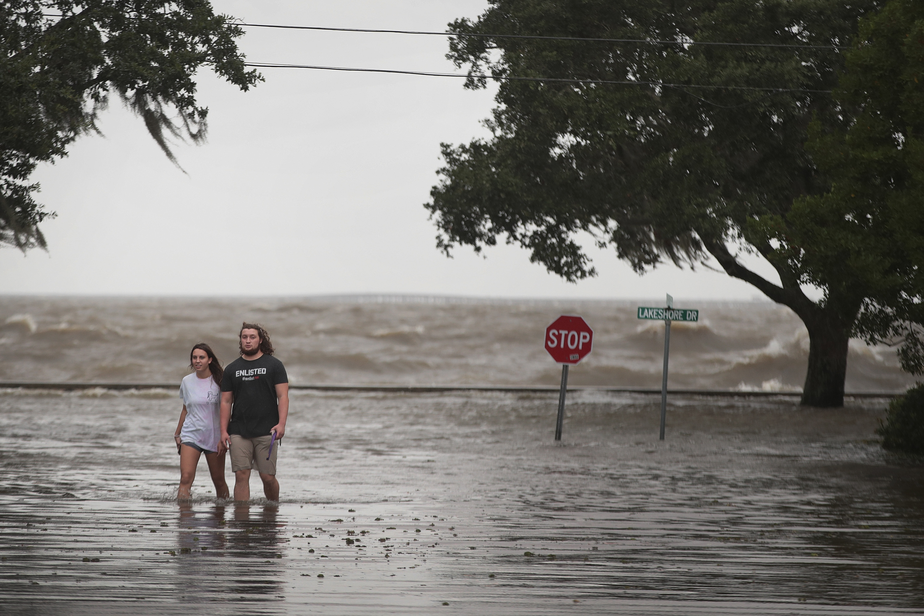 People walk along a flooded road.