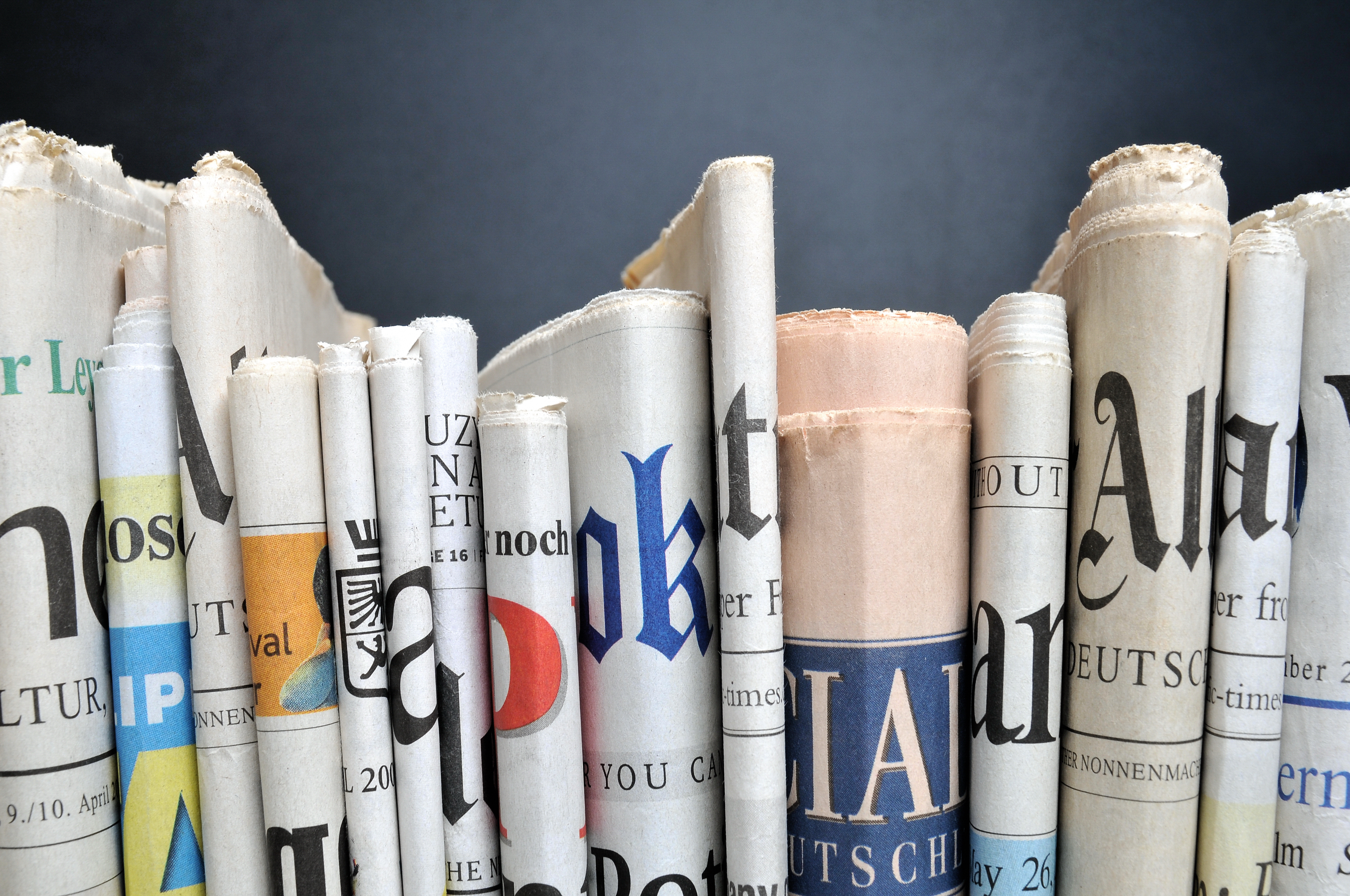 Folded newspapers stacked to see partial headlines