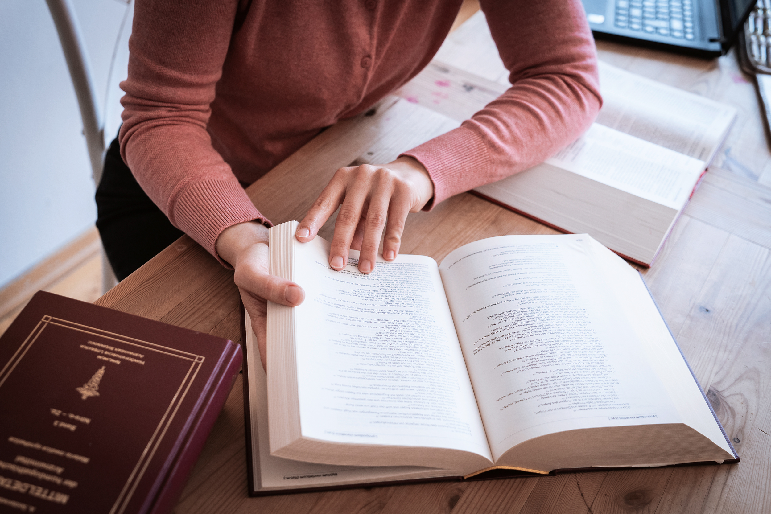 Jelena, die Homöopathin, sitzt an einem Tisch, vor ihr ist ein Lehrbuch aufgeschlagen