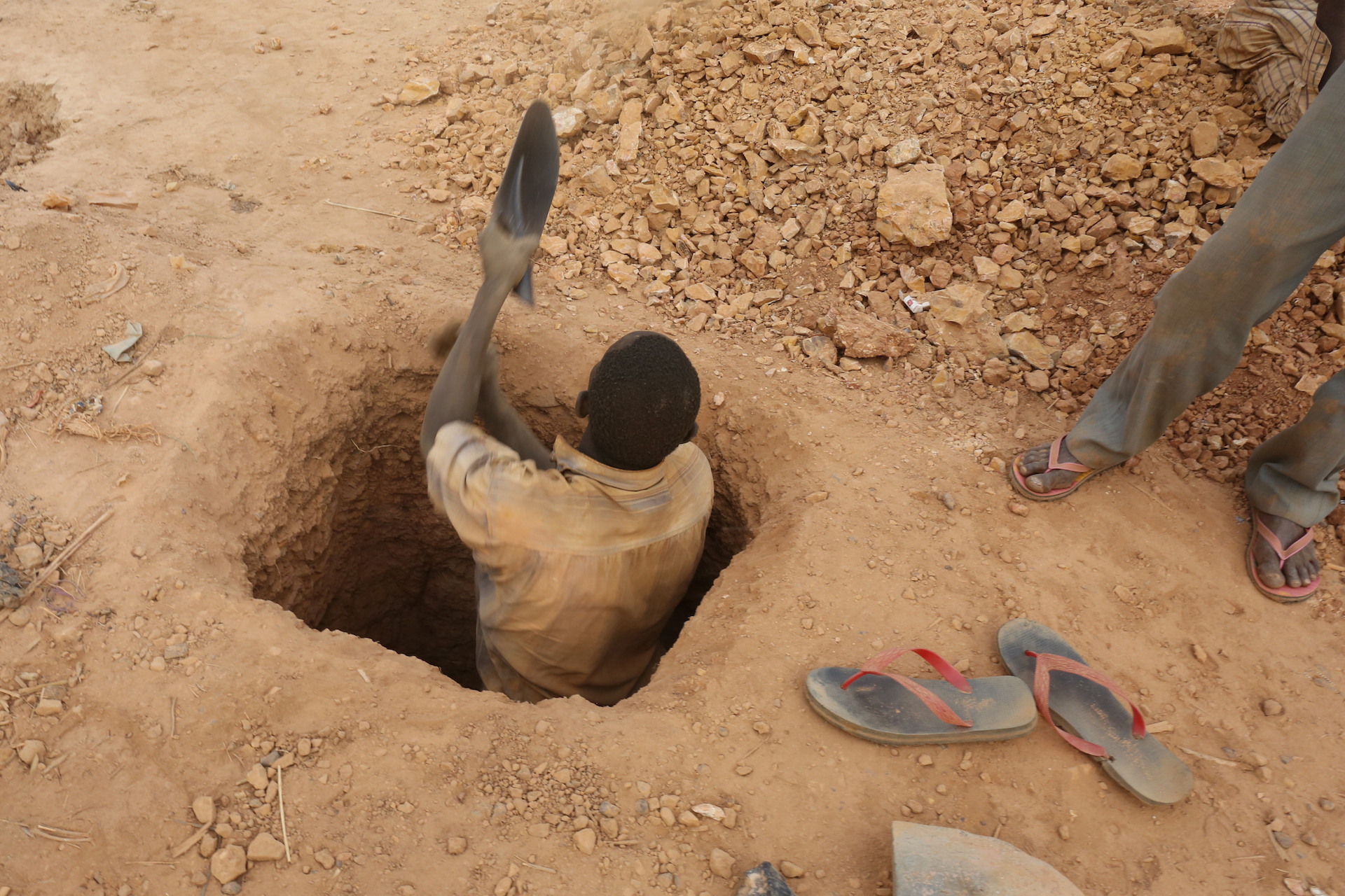 A miner digs a new shaft with the head of a shovel.