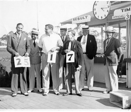 Baseball greats and racing fans: (front, L to R) Dizzy Dean, Babe Ruth, and Rabbit Maranville hold numbers that were hand placed on the odds board. Behind are the three judges Sid Harris, Tom and Heuse Gregory and odds board number placer.