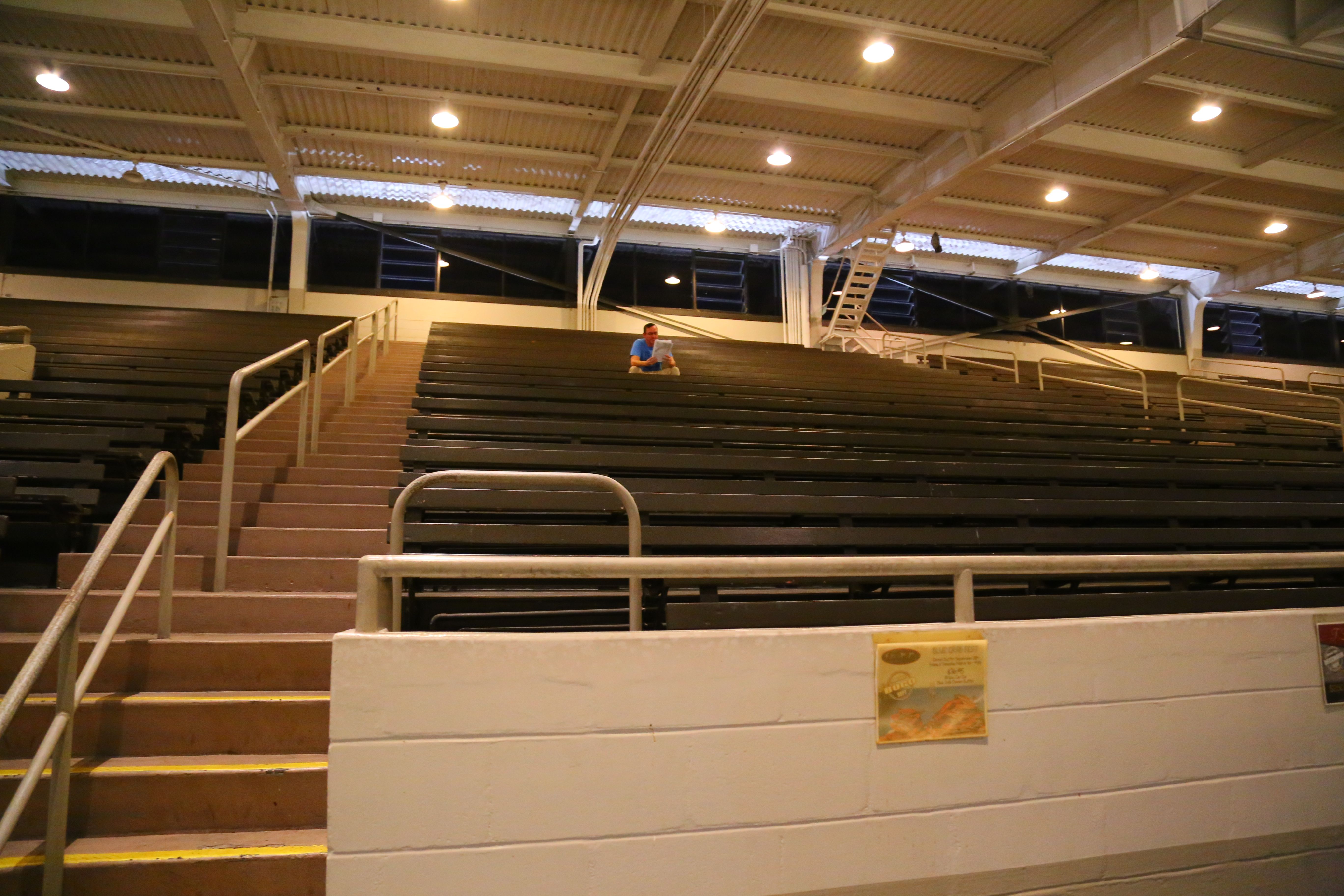 The writer sitting in the mostly empty grandstand reading the program, August 2019
