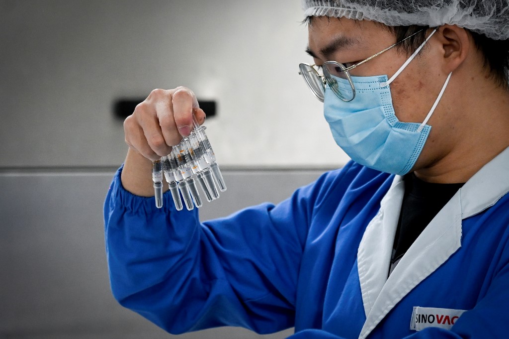 A Sinovac staff member inspects vaccine syringes. WANG ZHAO / AFP