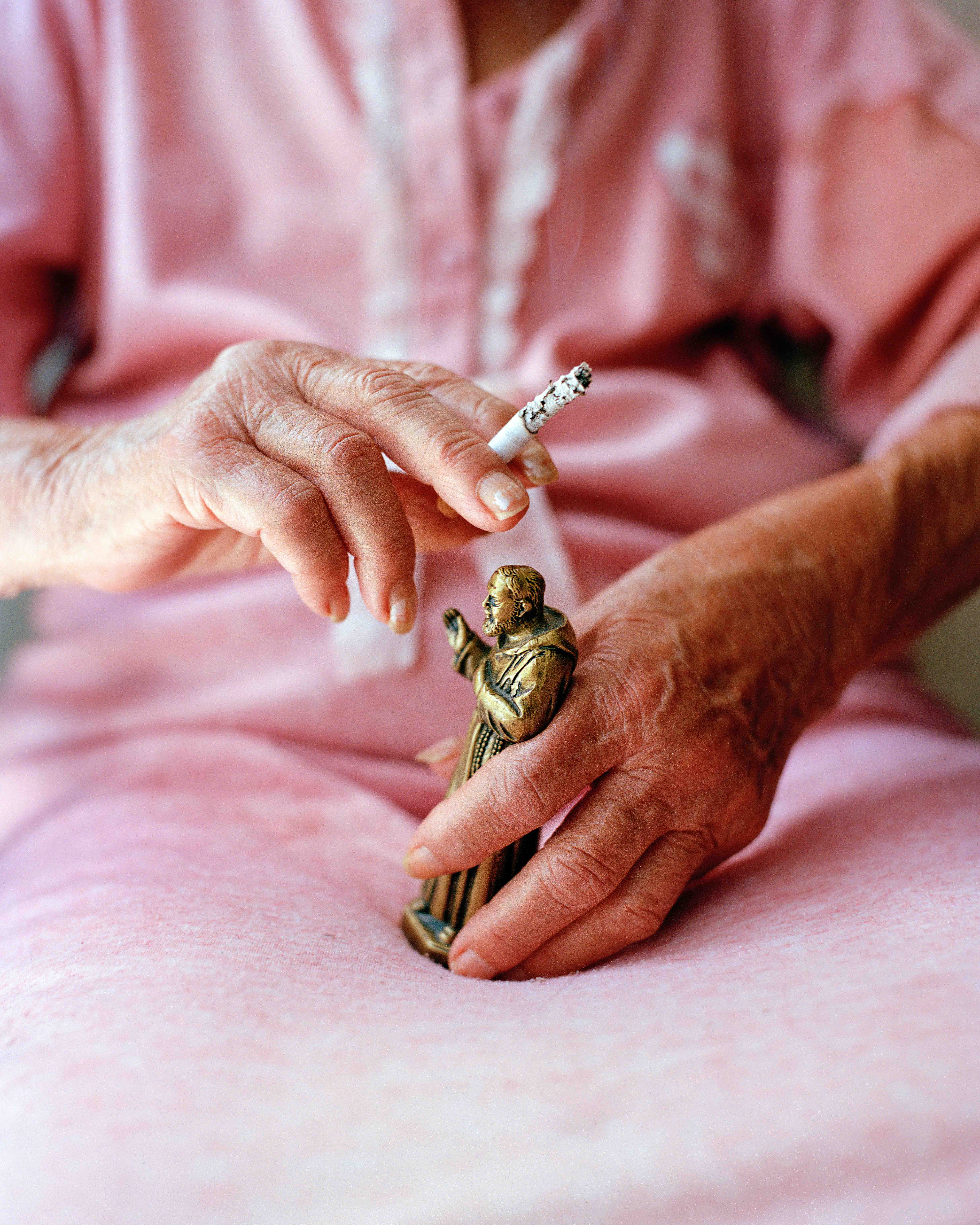 Una donna tiene in mano una statuetta di Padre Pio, fotografia di Sam Gregg