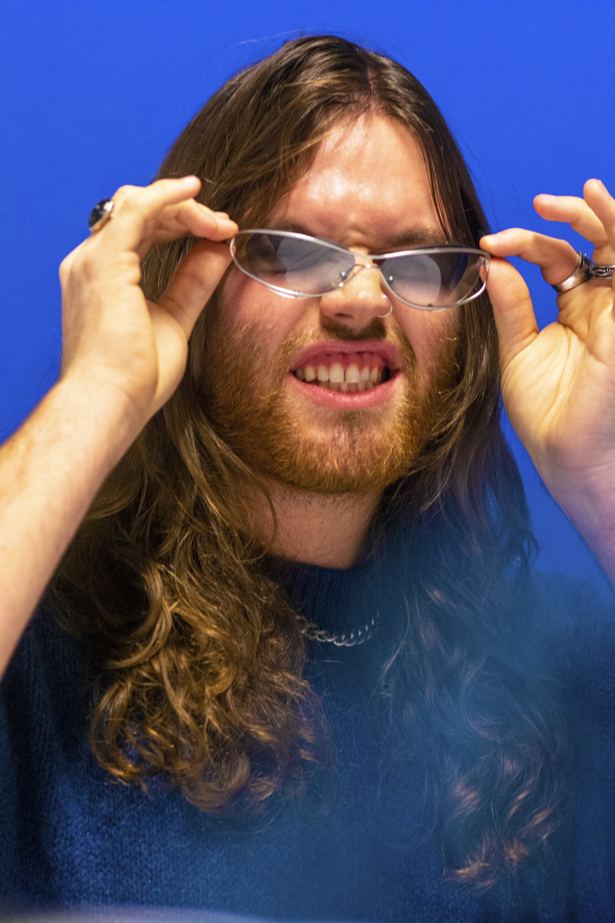 Man with blue jumper, metallic chain and sunglasses. Photographed by Marcus Branch.