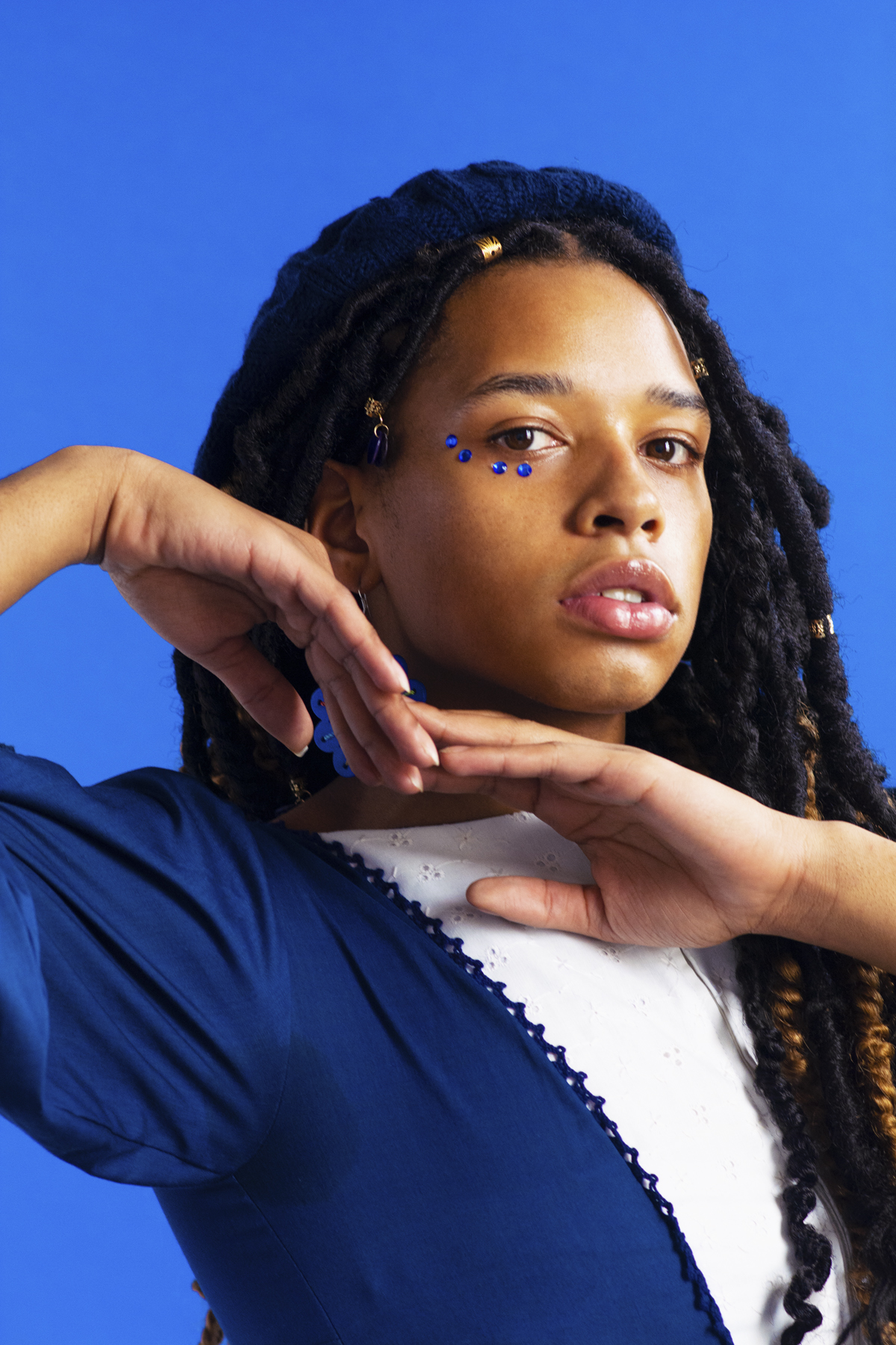 Individual with face gems in a navy blue blouse. Photographed by Marcus Branch.