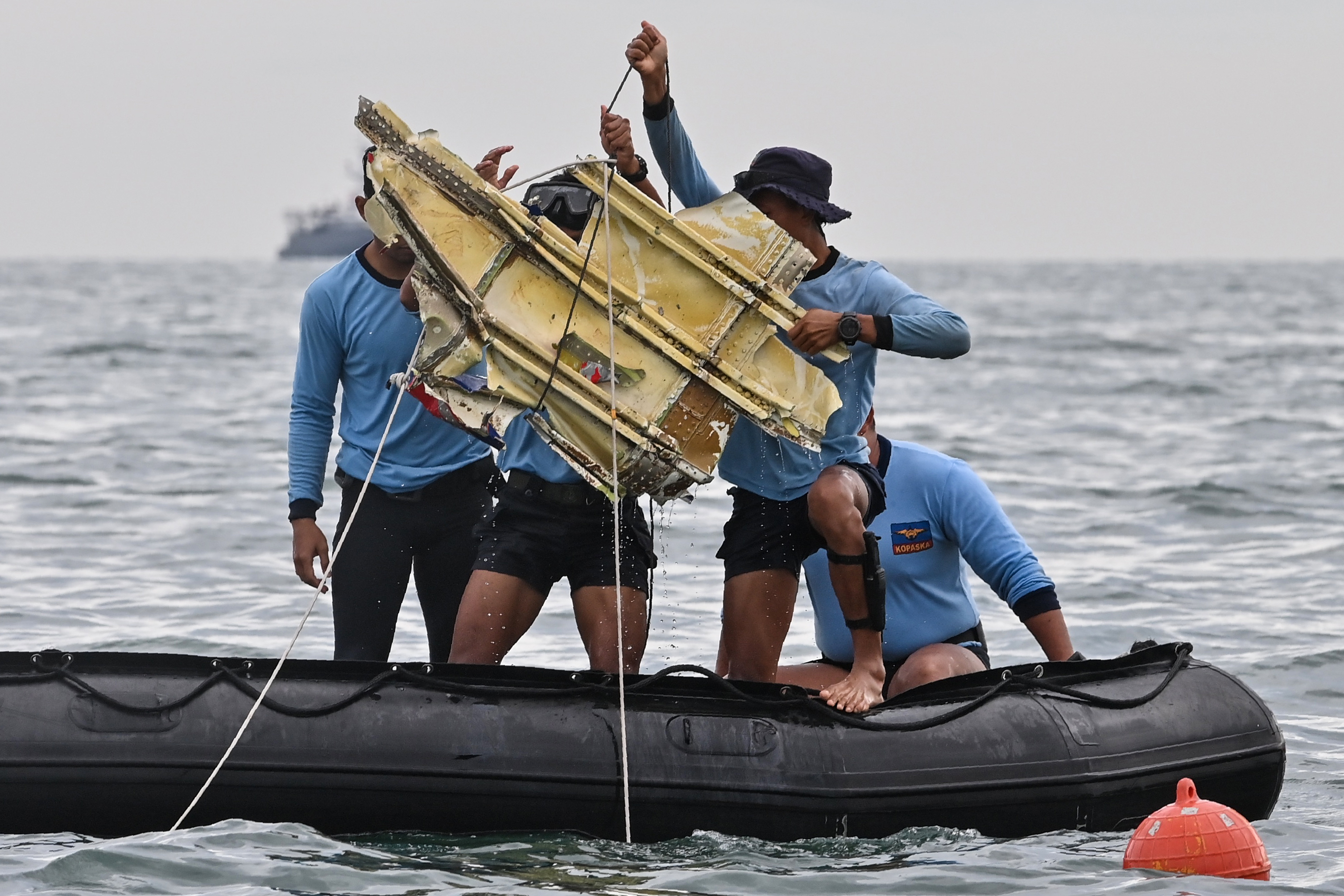 Indonesian navy divers hold up wreckage. (AFP PHOTO BY ADEK BERRY) 