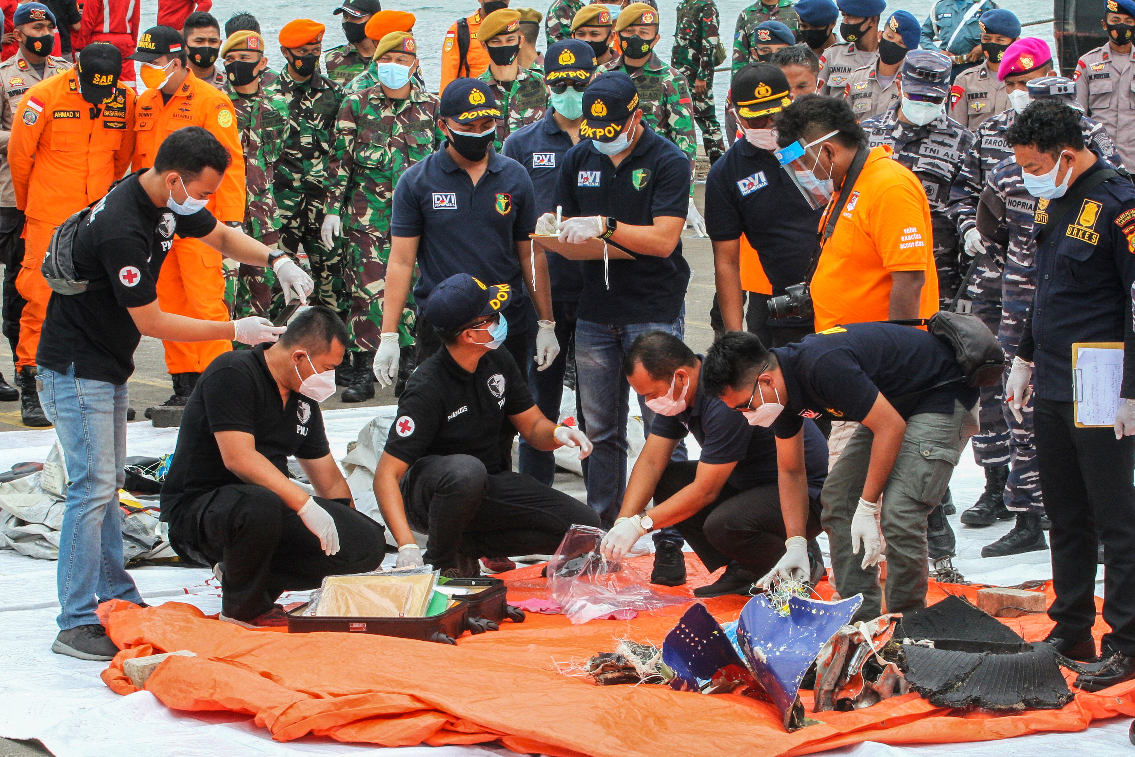 Rescue workers inspect recovered items and debris at the port in Jakarta on Jan. 10, 2021. (AFP PHOTO BY DANY KRISNADHI) 