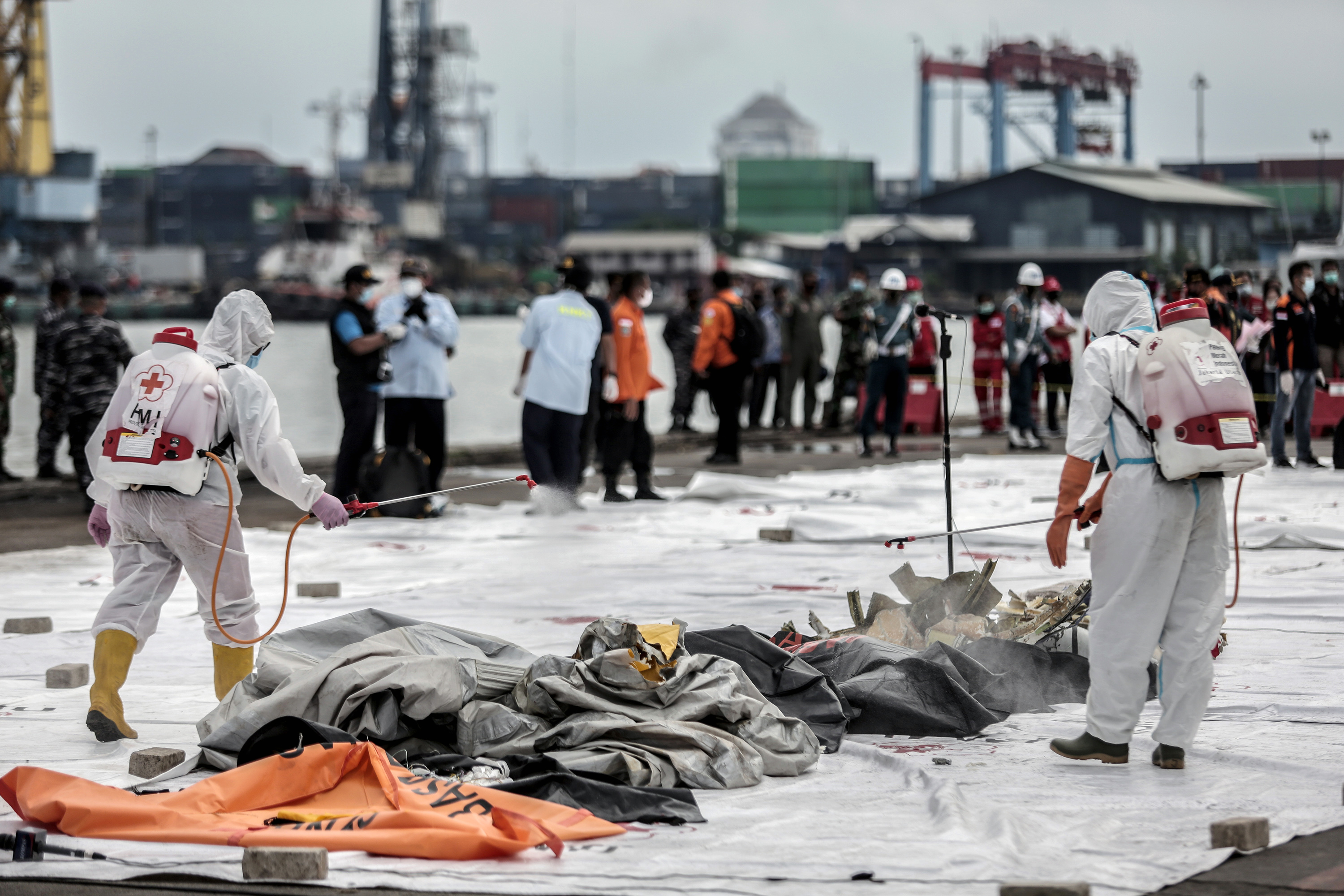 Health workers spray disinfectant over body bags. (AFP PHOTO BY ADITYA AJI)