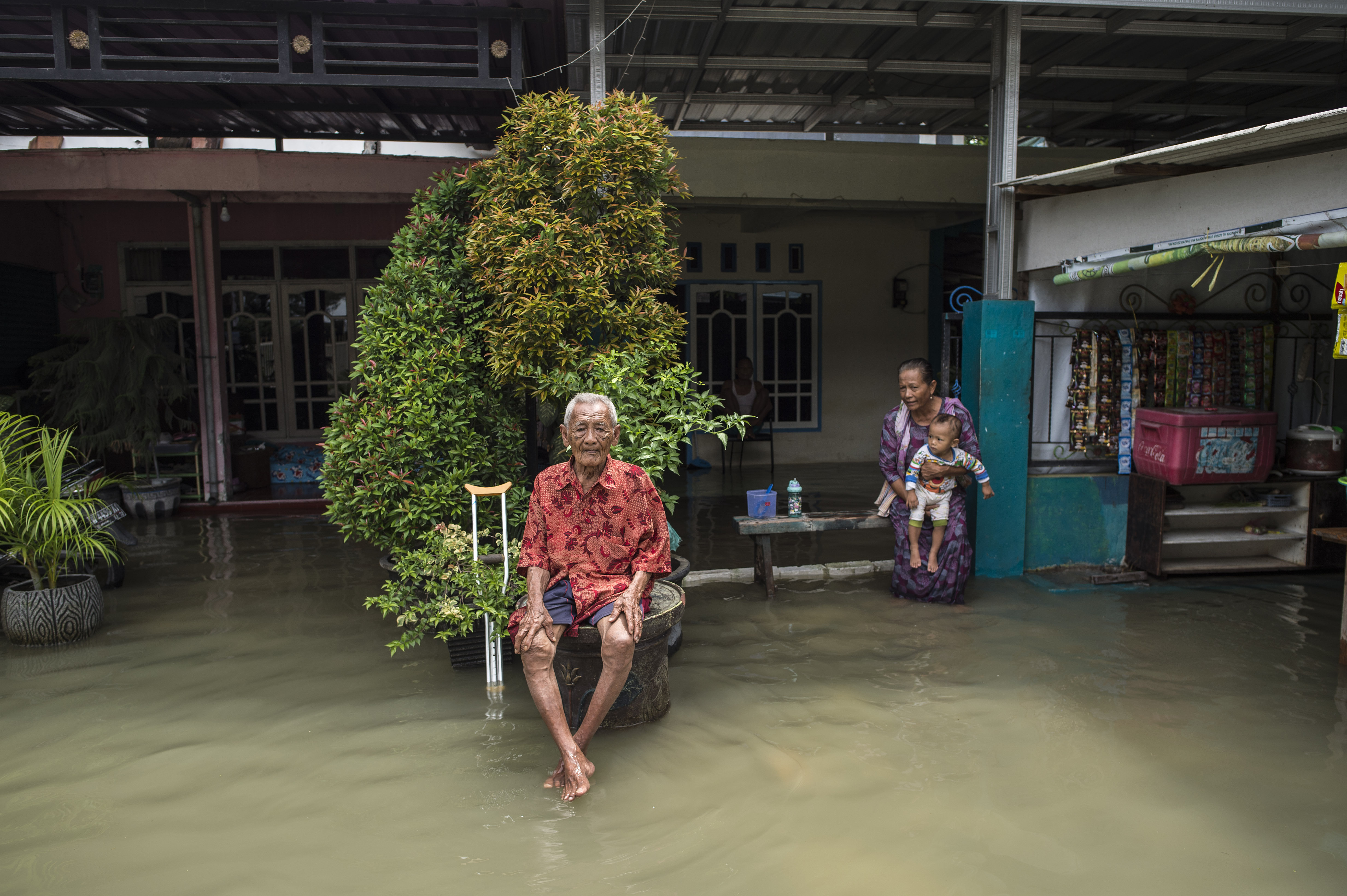 Elderly residents sit outside their flooded home. (PHOTO: AFP / Juni Kriswanto) 