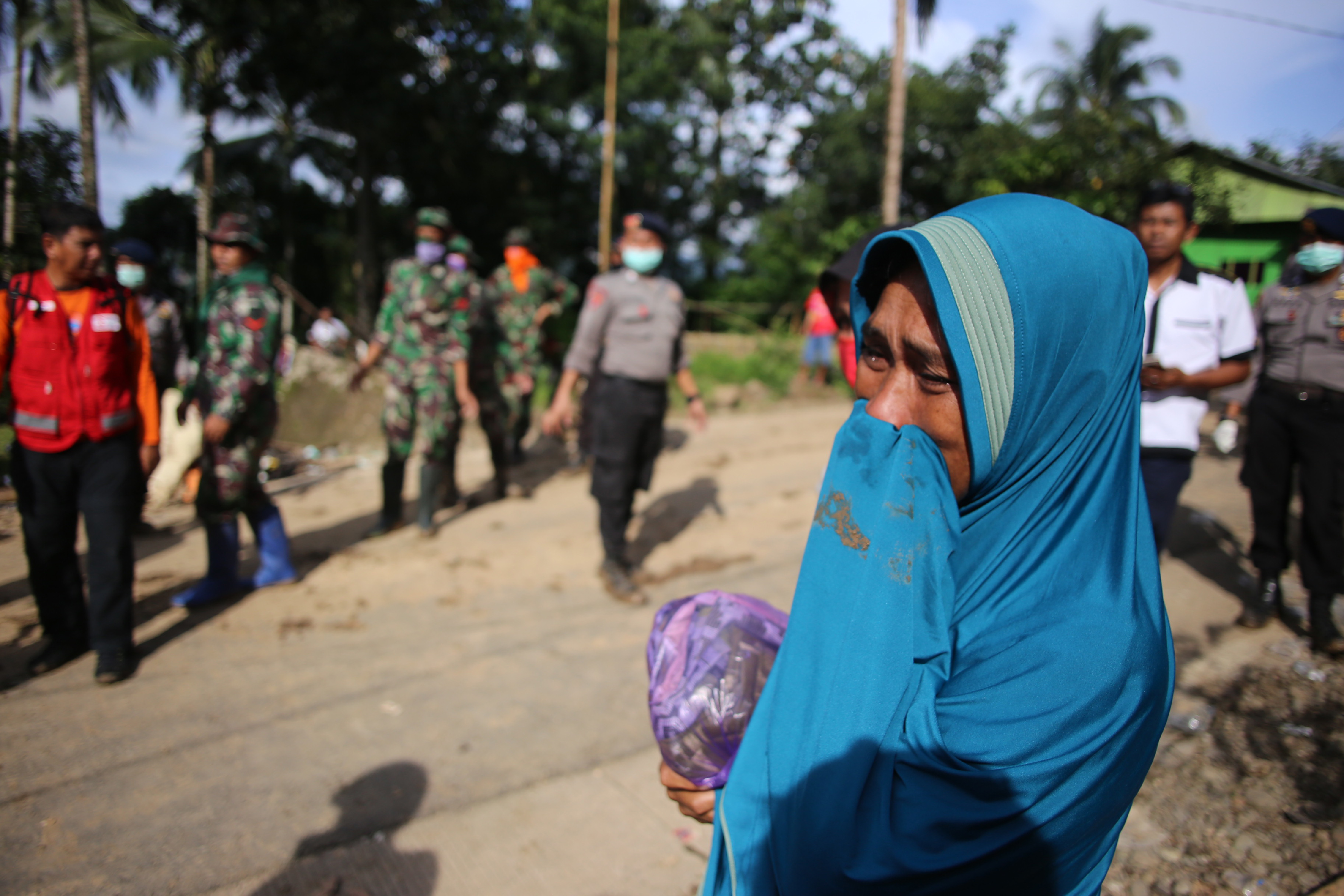 A woman cries as Indonesian search and rescue personnel work in the background in the Manuju subdistrict of South Sulawesi. (PHOTO: AFP / DAENG MANSUR) 