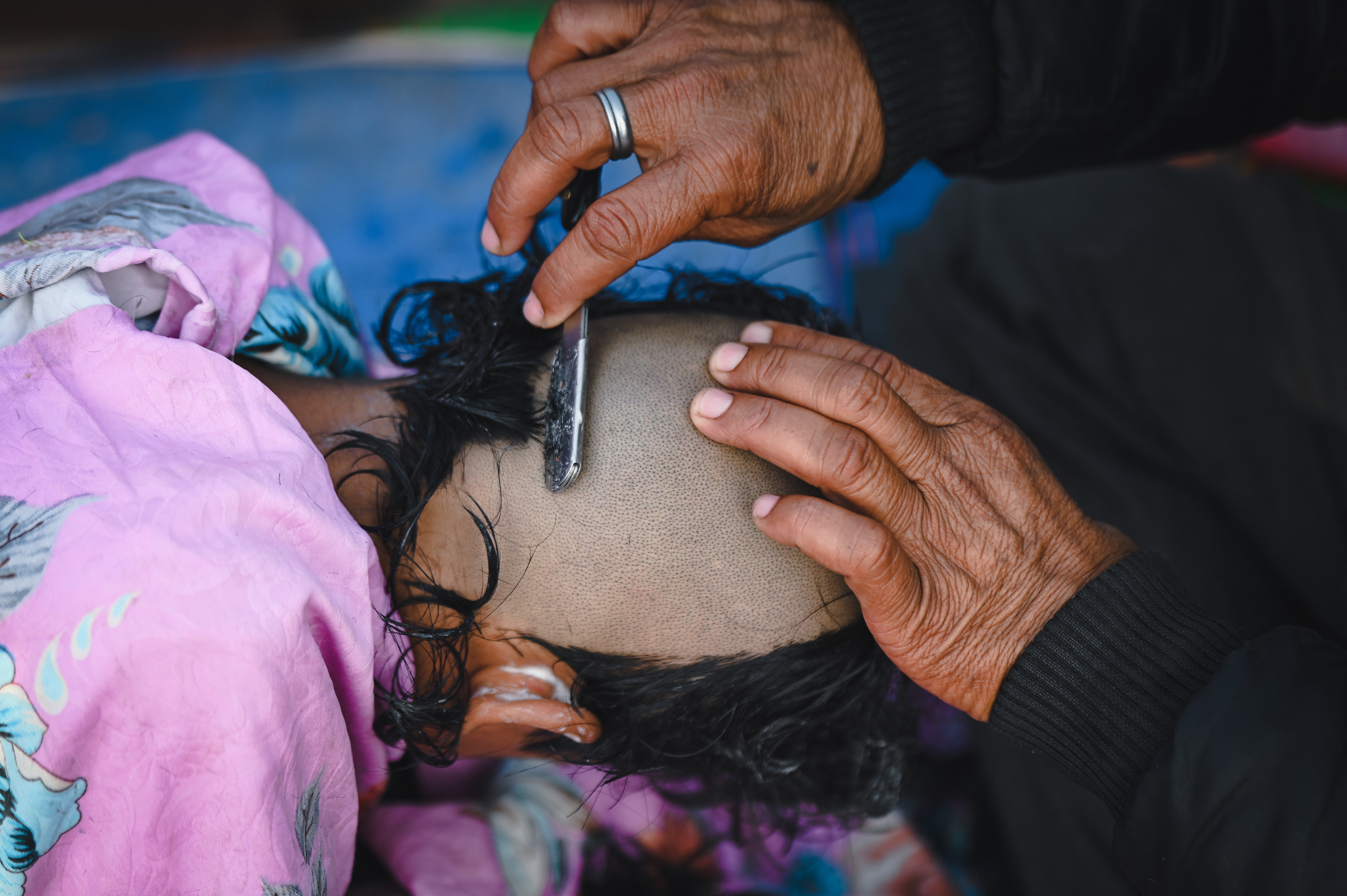 boy getting his head shaved at kumbh mela