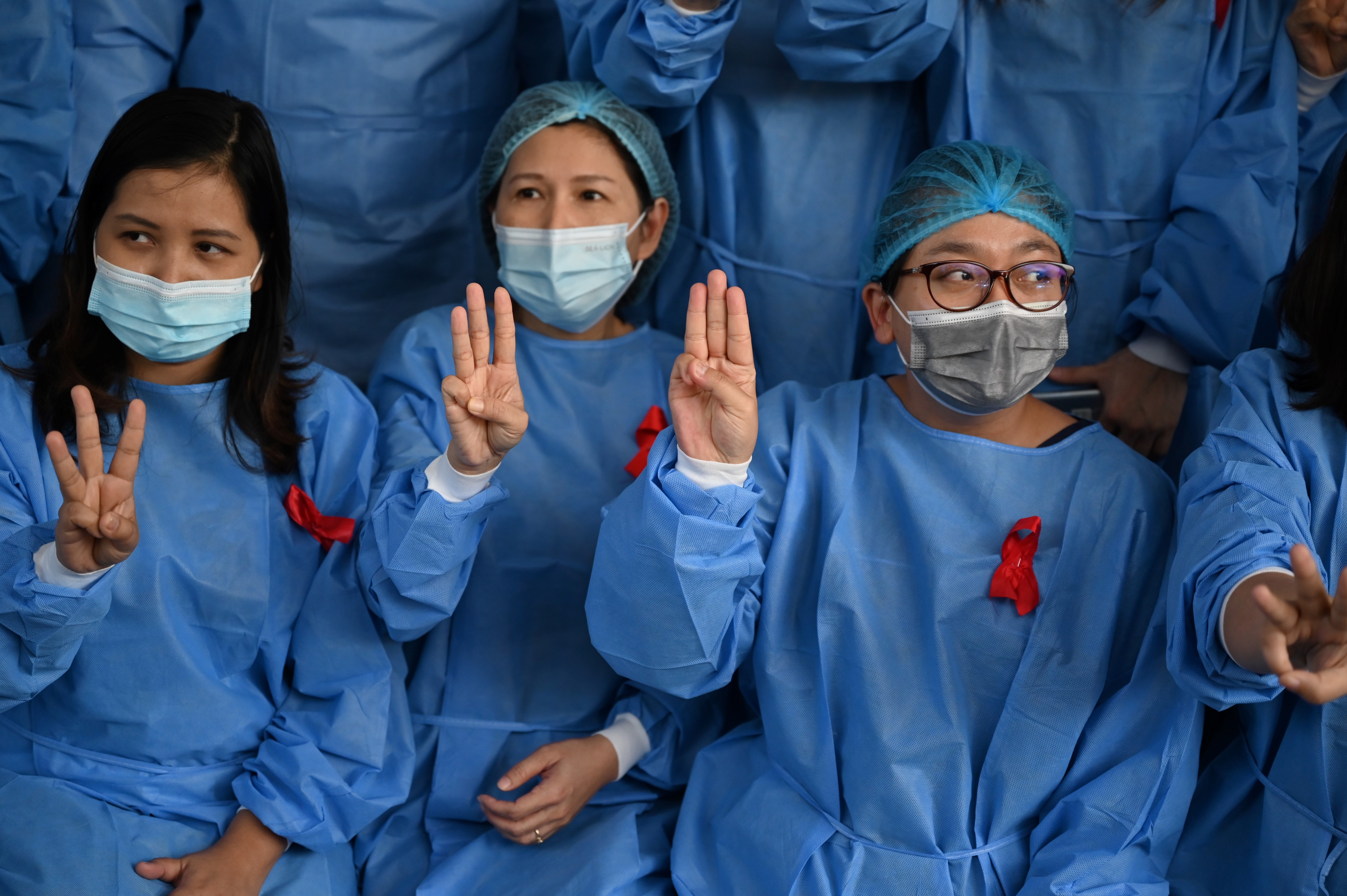 Medical staff at the Yangon General Hospital wear red ribbons and display the three finger salute, a sign of protest popularised by protesters in neighboring Thailand. (PHOTO: AFP, STRINGER)