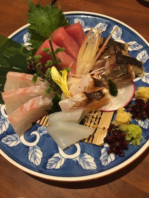 An arrangement of sashimi and wakame seaweed on a white and blue plate.