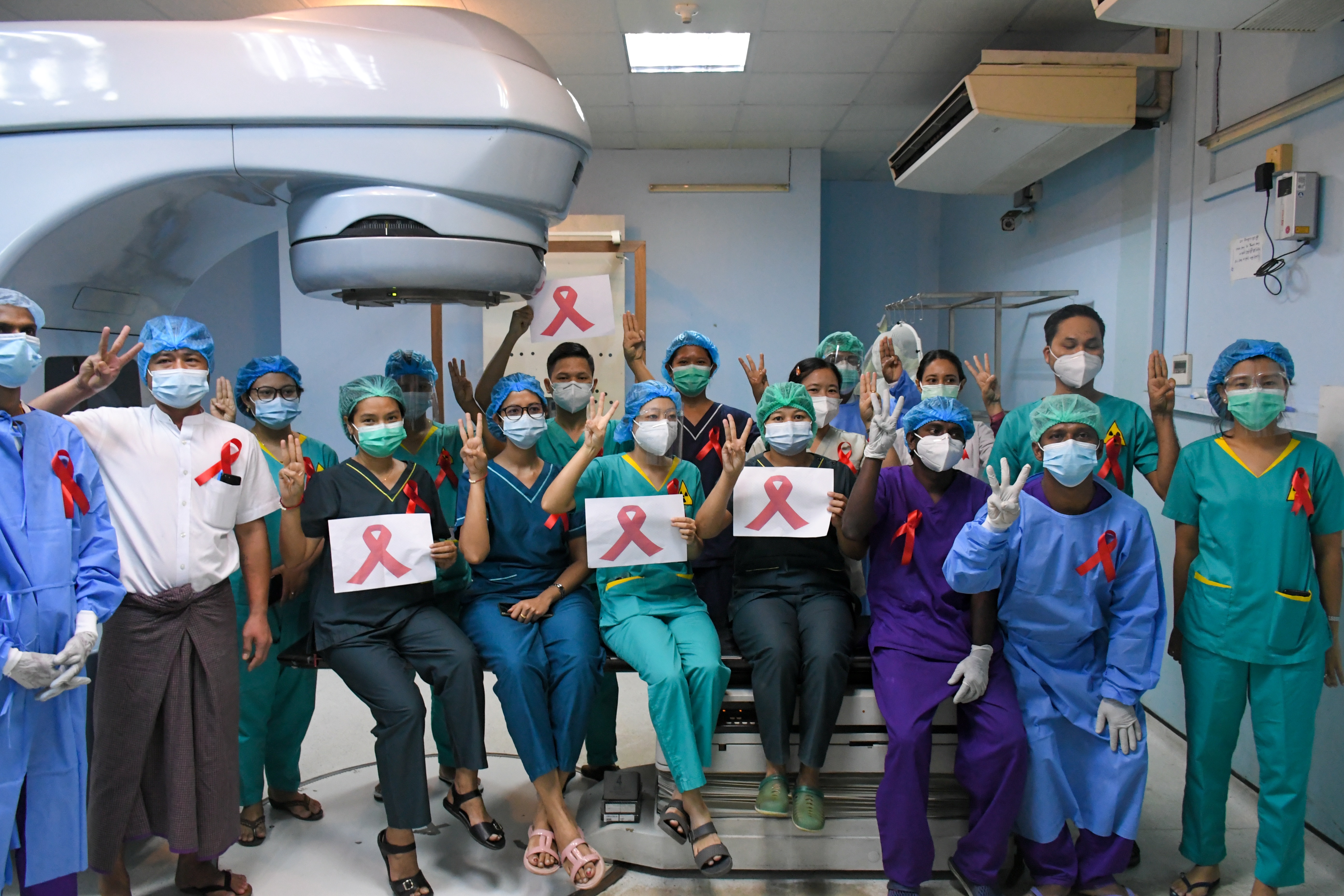 MEDICAL STAFF WEAR RED RIBBONS AND DISPLAY THE THREE FINGER PROTEST SALUTE AT THE YANGON GENERAL HOSPITAL. PHOTO: AFP