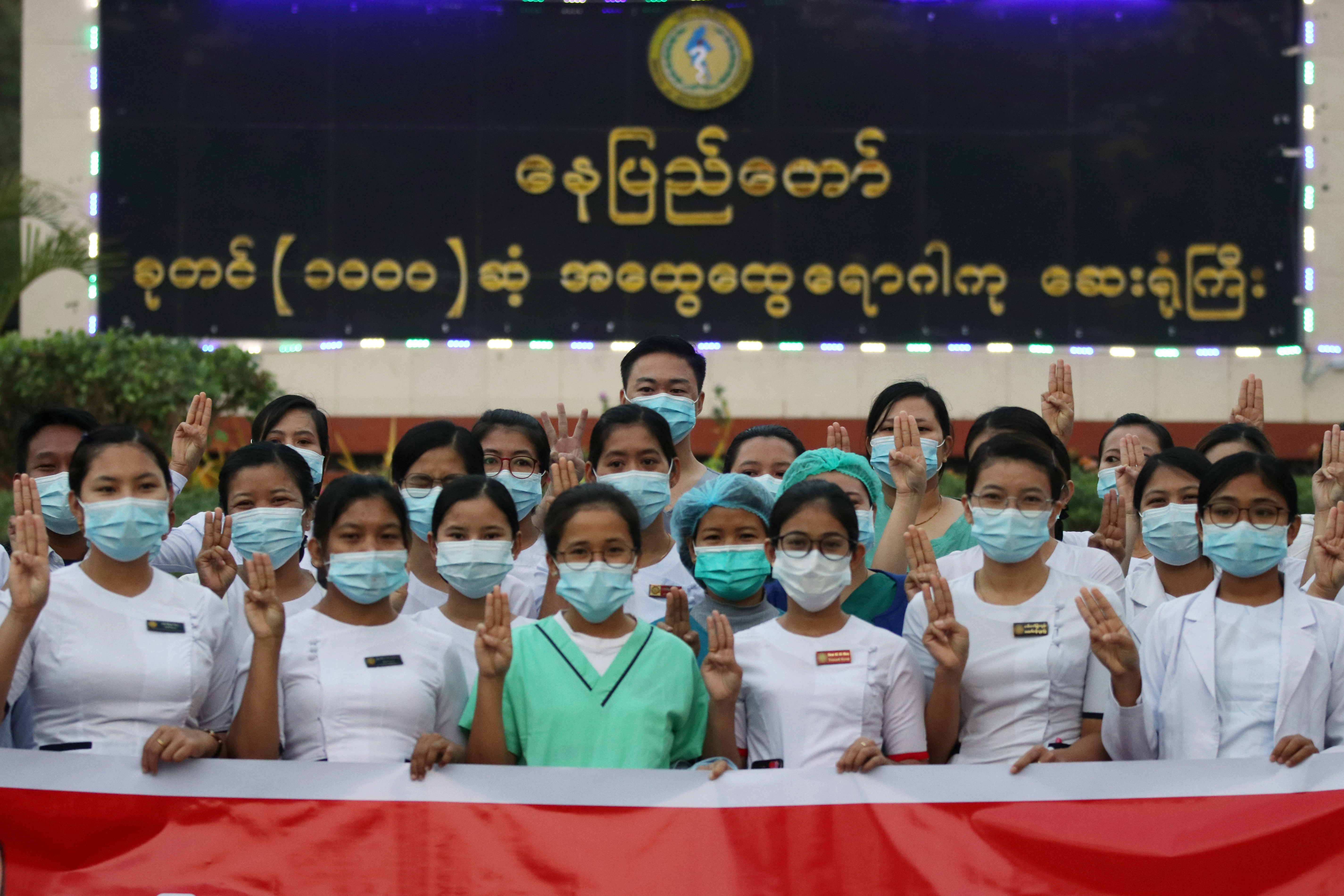 Medical staff hold up a three-finger salute as they pose for a photo in protest against the military coup at a hospital in Naypyidaw. (PHOTO: AFP)