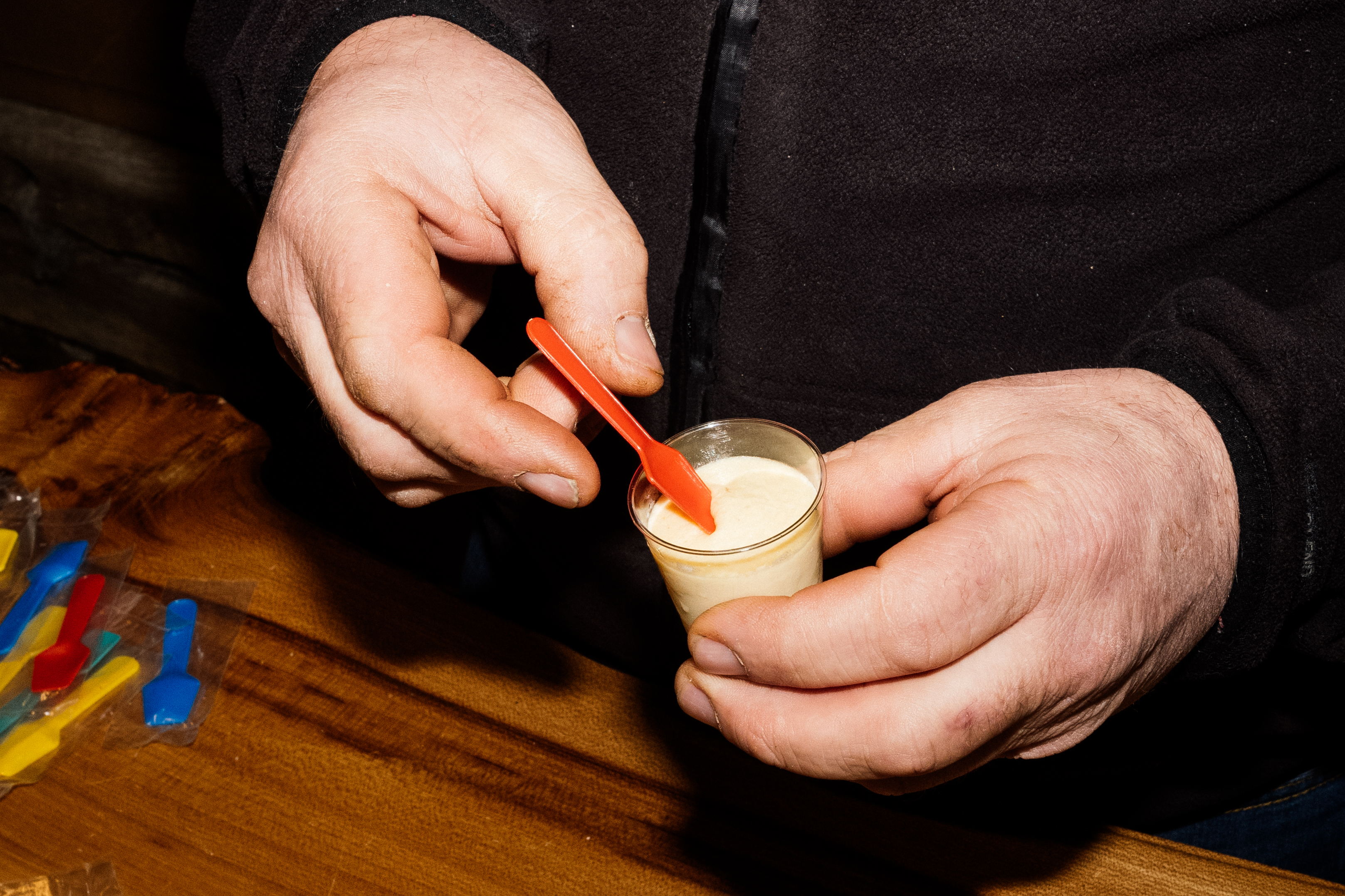 Patrice Riauté, pork ice cream – Patrice holding a tiny glass and sticking an orange plastic spoon in it.