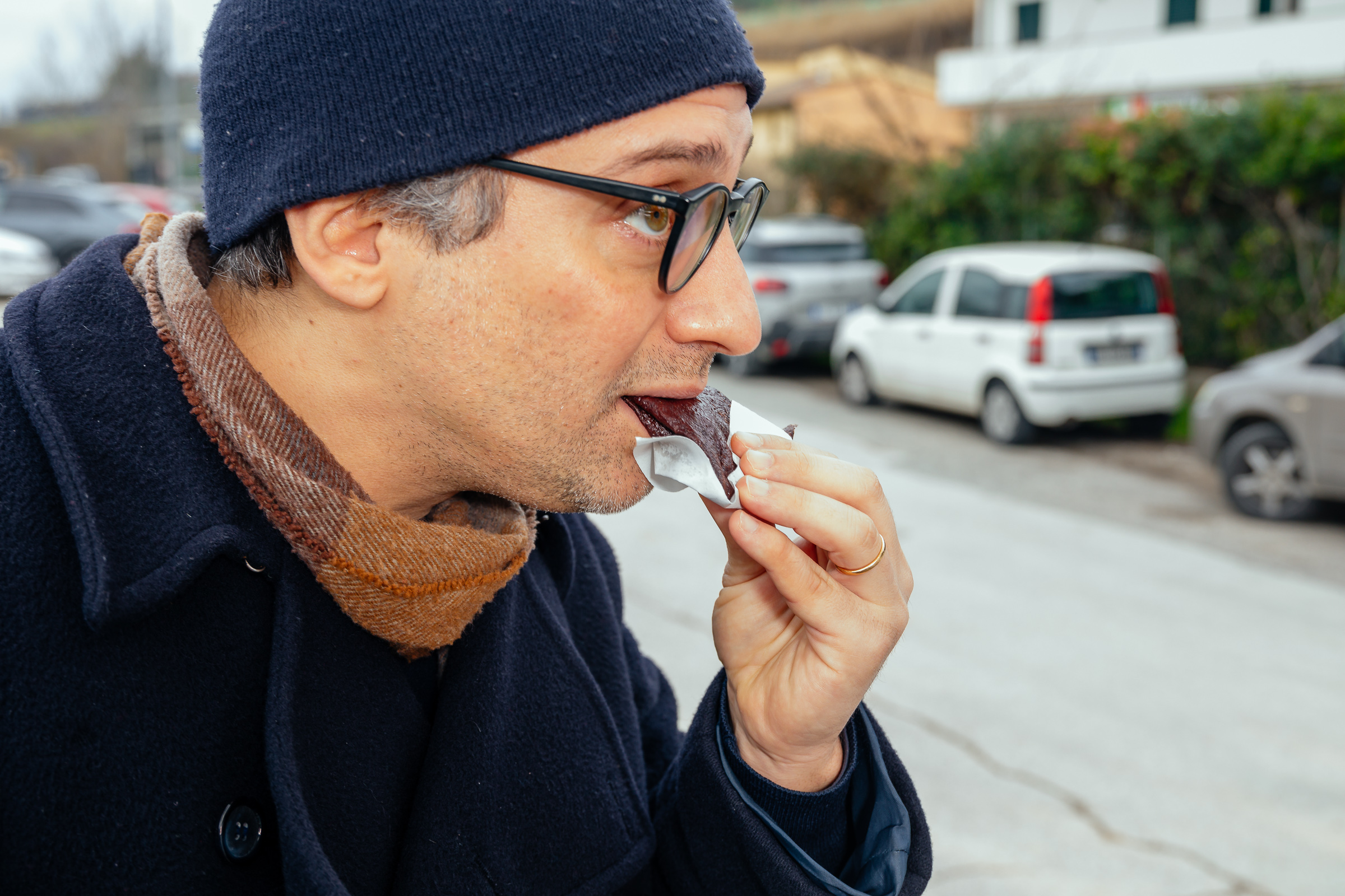 Man met een muts op eet een rovetini op straat.
