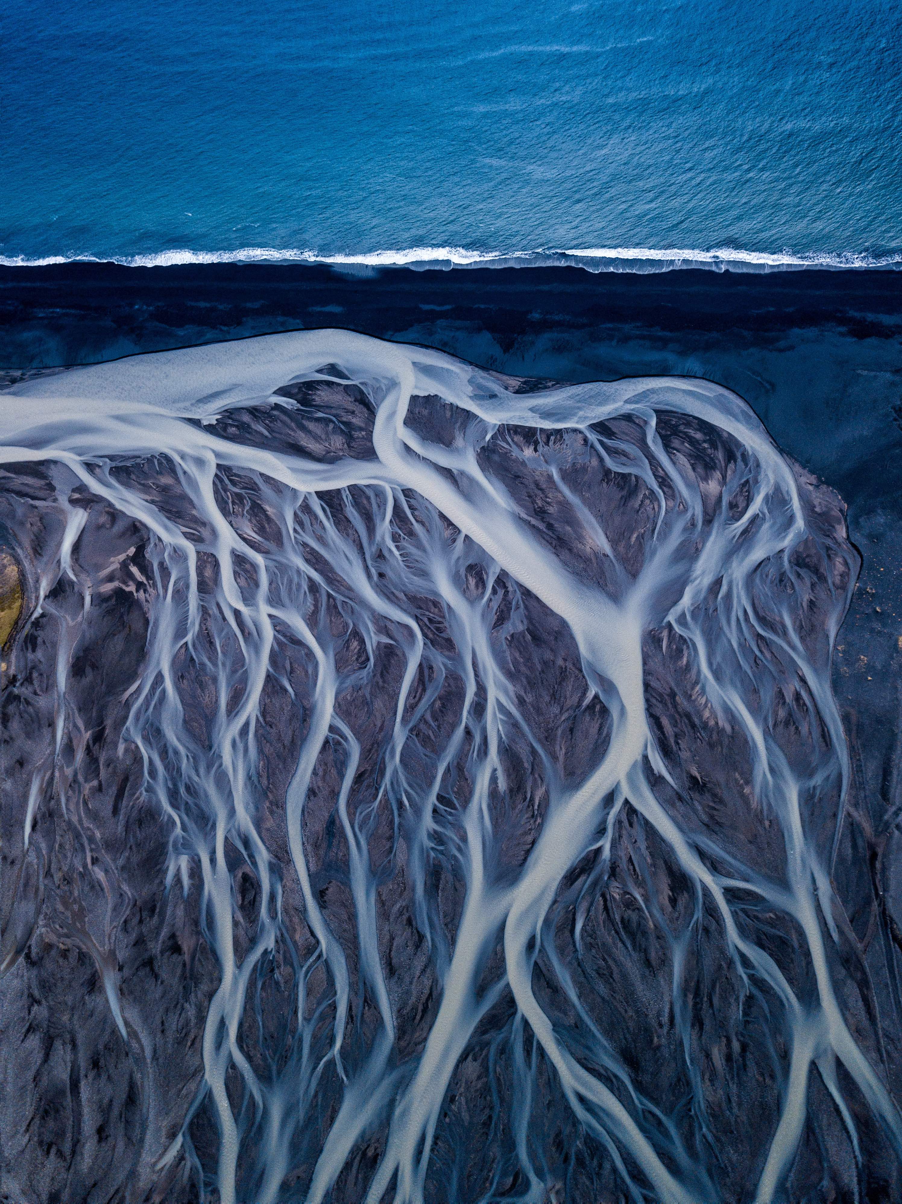 Sungai glasial mengaliri pasir hitam menuju Atlantik