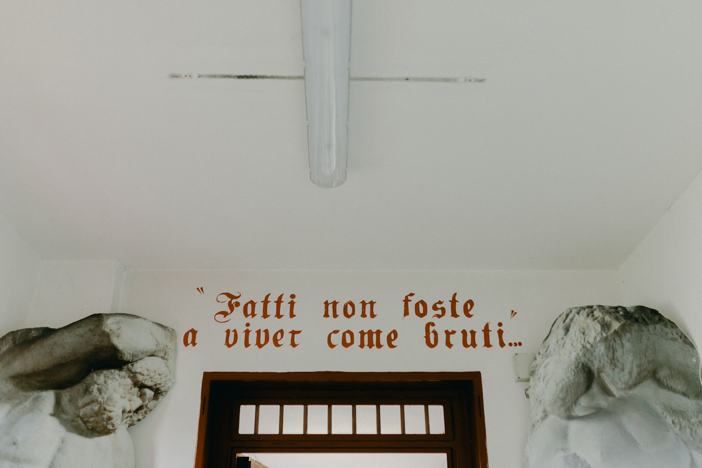 Giotto Bakery – A gothic red font spelling the famous Dante quote. The writing is on top of a red gate, which has decals of marble statues on either side.