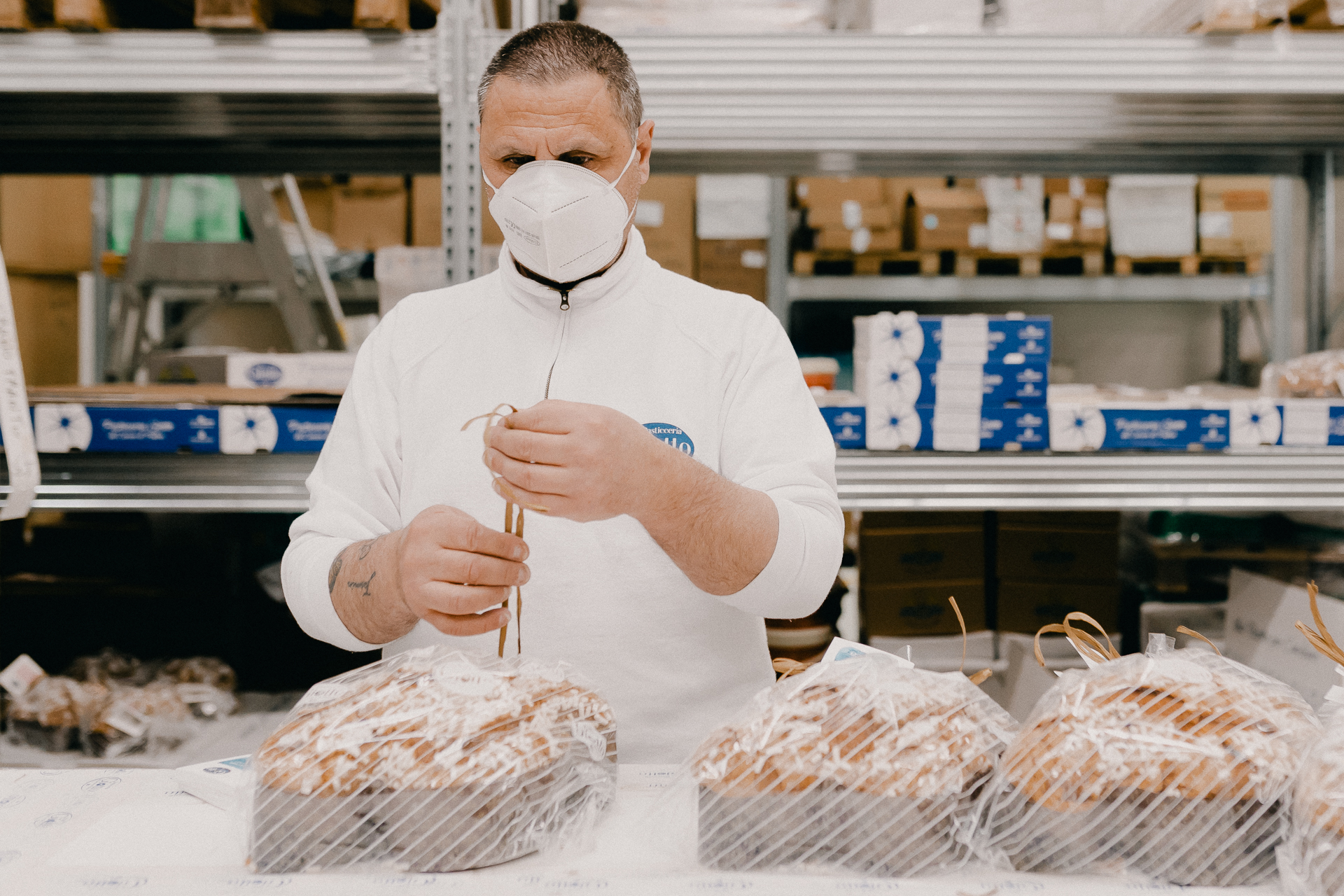 Giotto Bakery – A man tying up the colombe wrapped in a plastic foil with a beige string