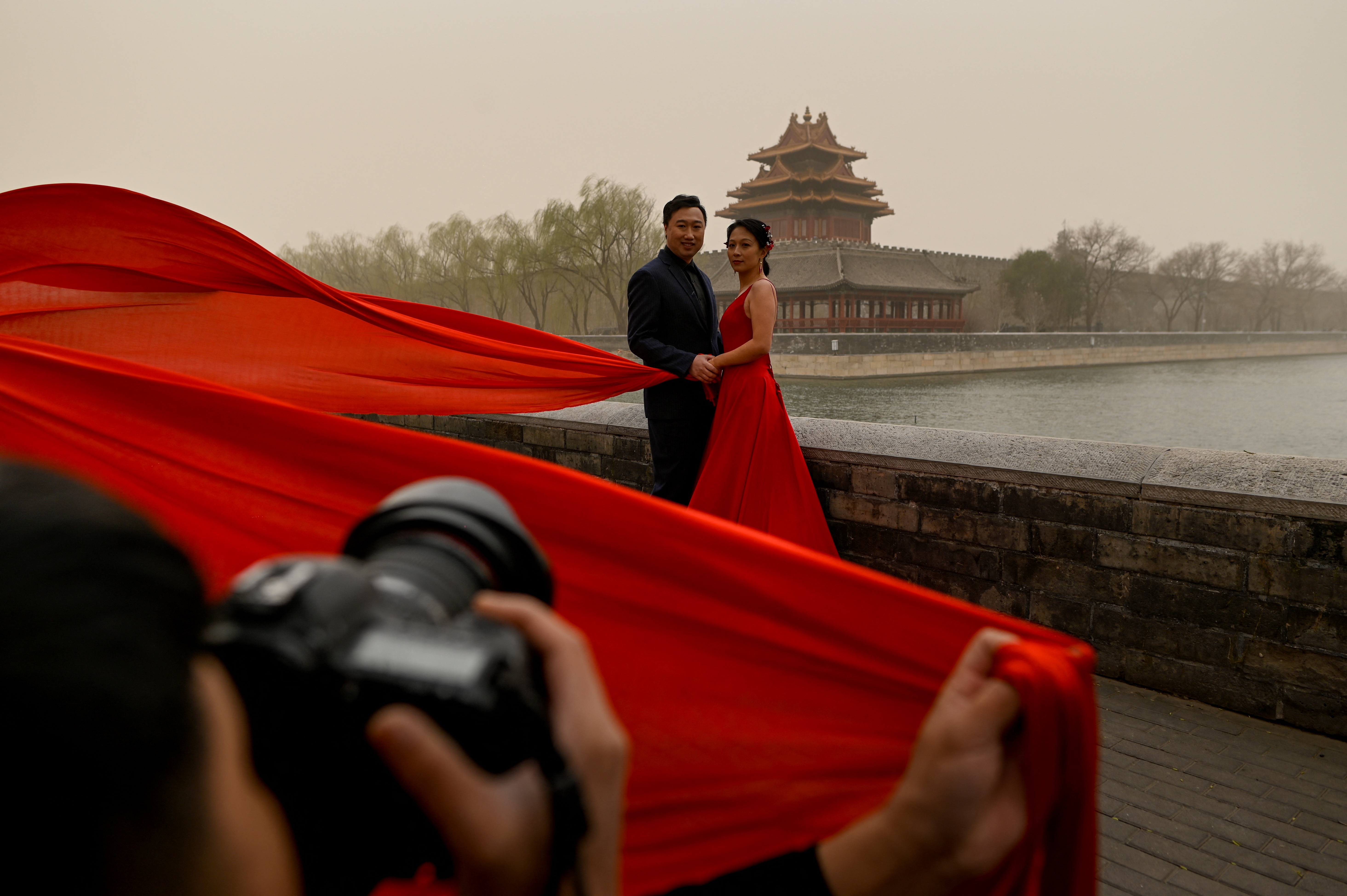 A couple poses for wedding photos outside the Forbidden City during the sandstorm