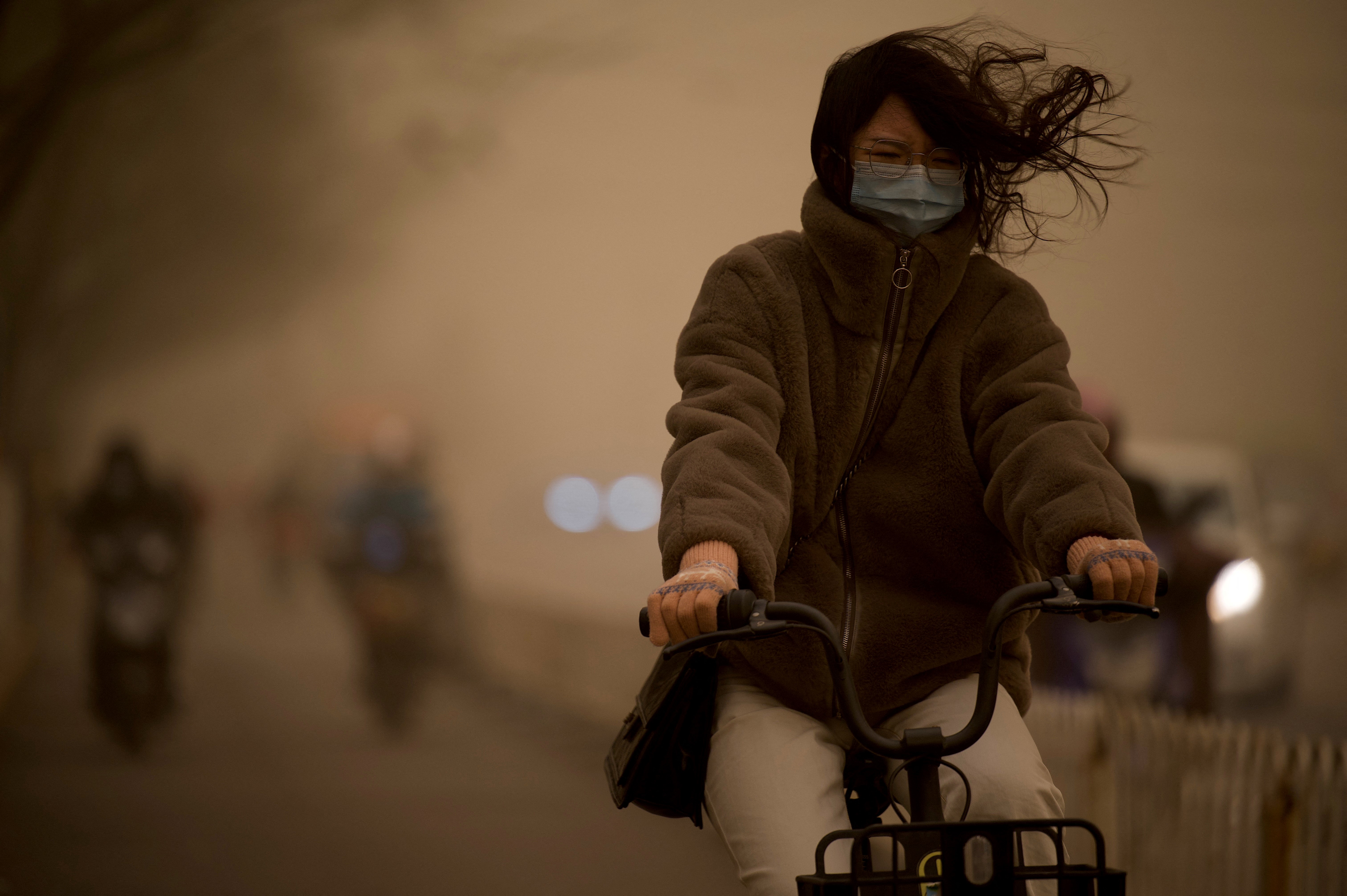 Woman cycles during Beijing sandstorm