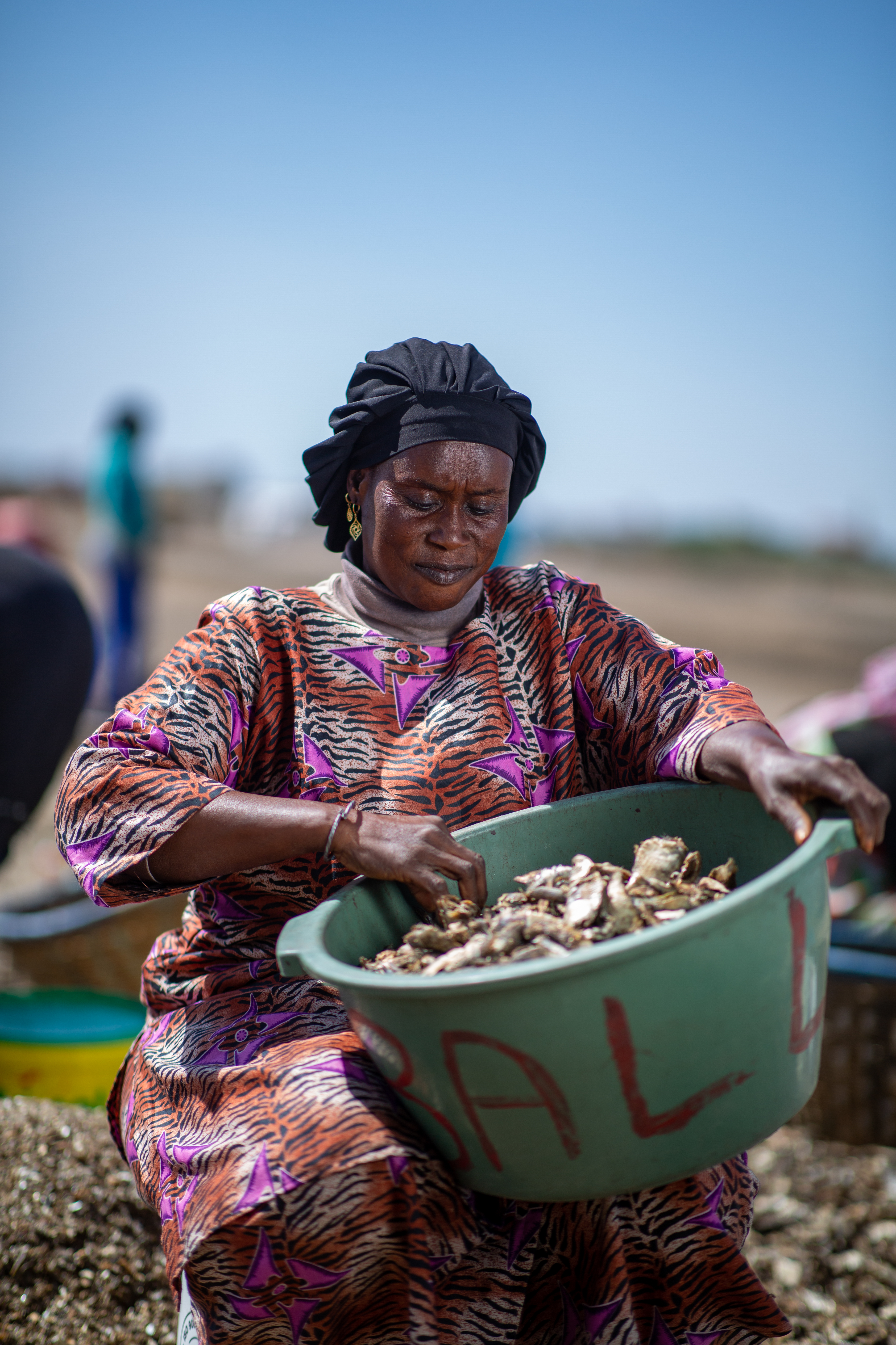 A woman sorts fish from a bucket.
