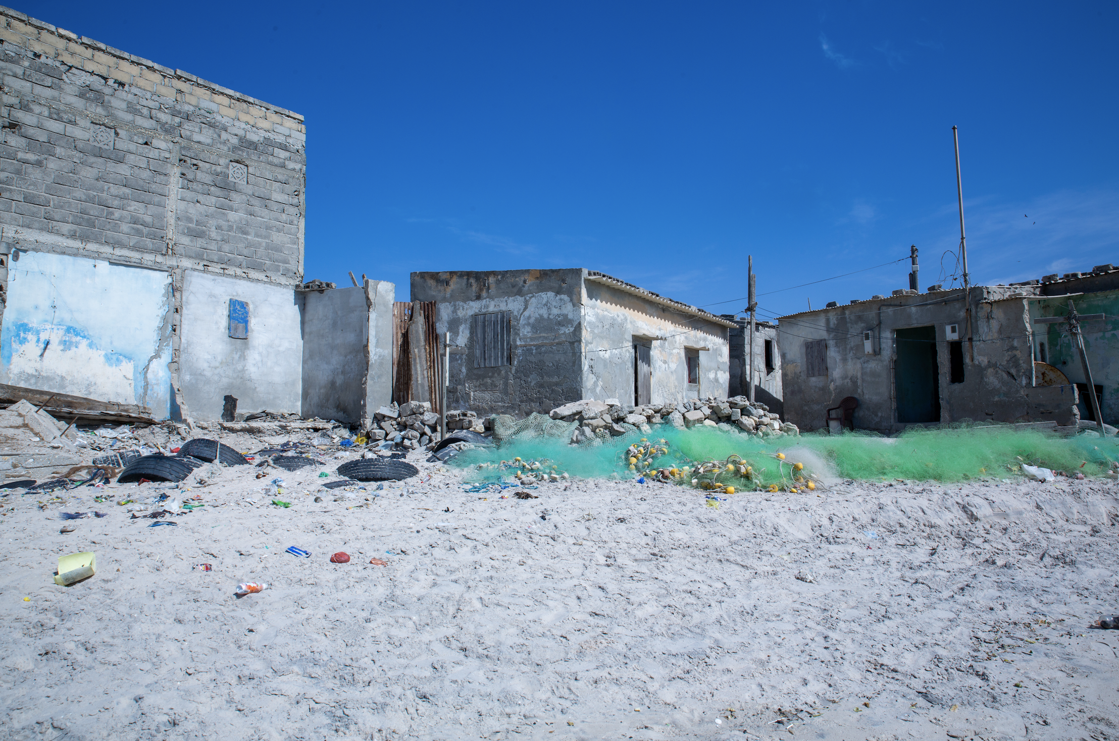 Fishing nets piled on the sand sit next to homes in Bargny.
