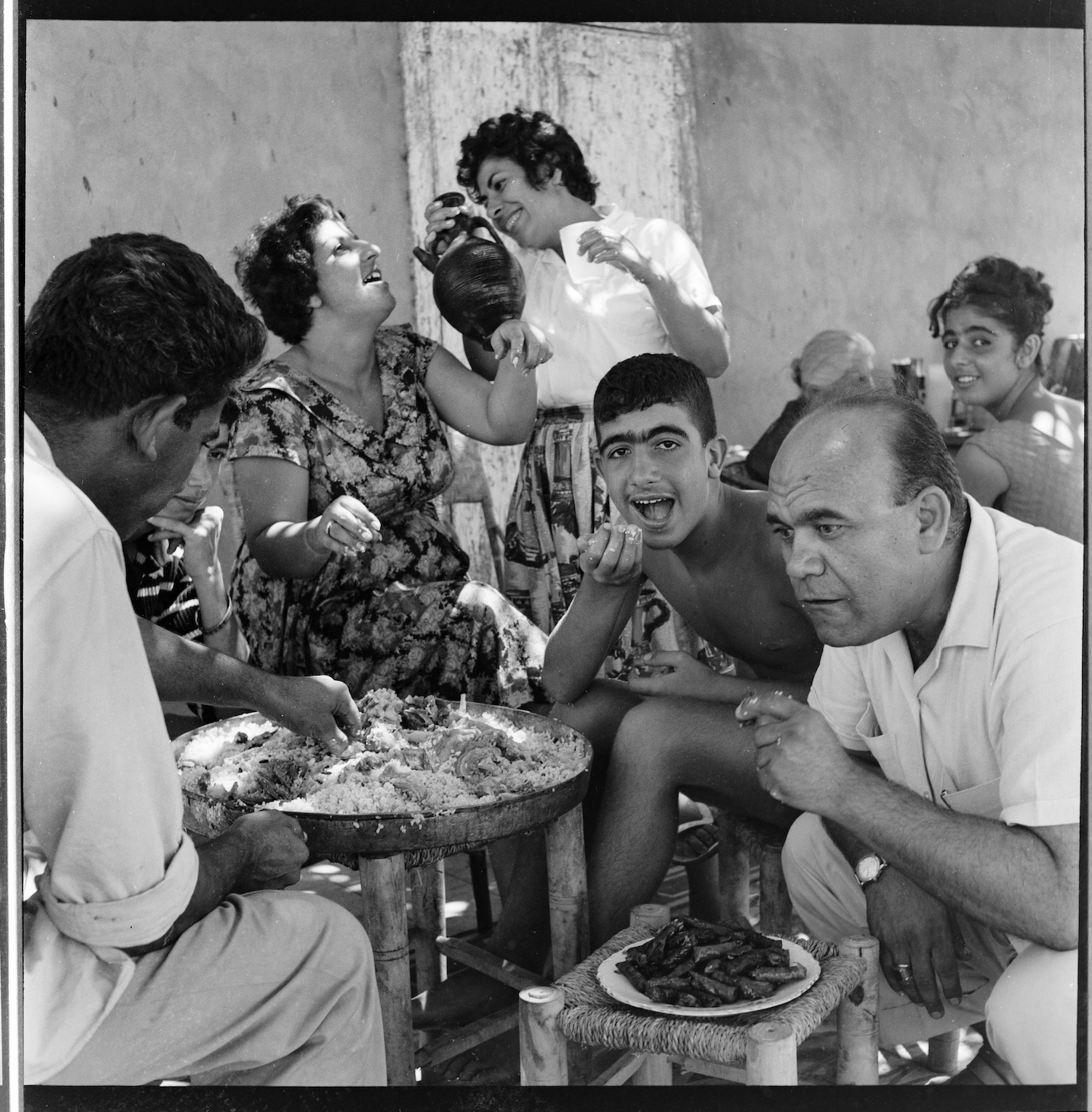 Kegham Djeghalian, Gaza photographer – men and women gathered around a large fattah dish, laughing, talking and eating with their hands.