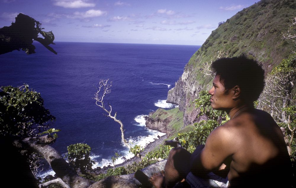 Seorang remaja duduk di atas tebing pulau Ata.