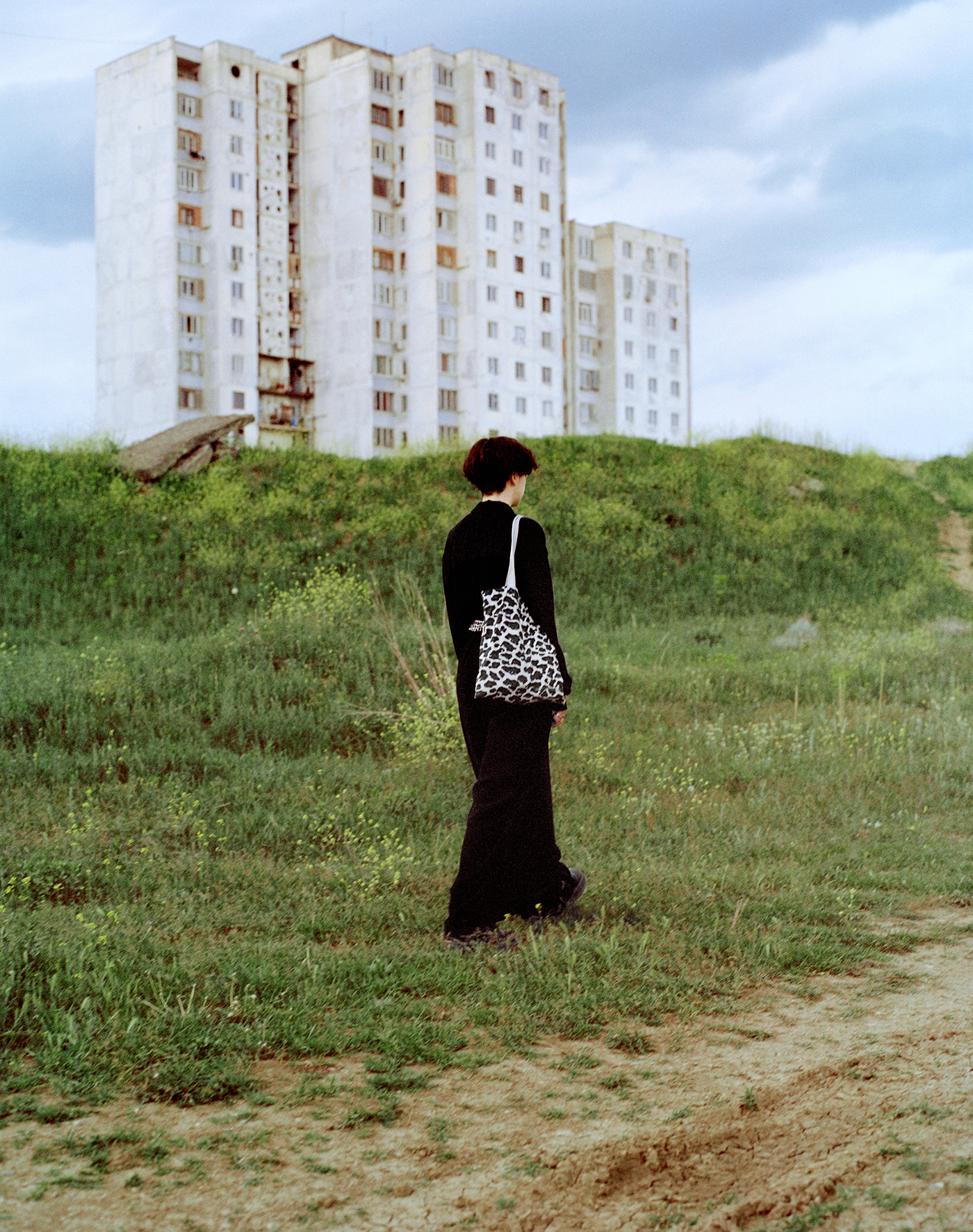 persona in parco con palazzo alle spalle, Everything ok not ok, giovani queer Tblisi, fotografia di Piet Oosterbeek