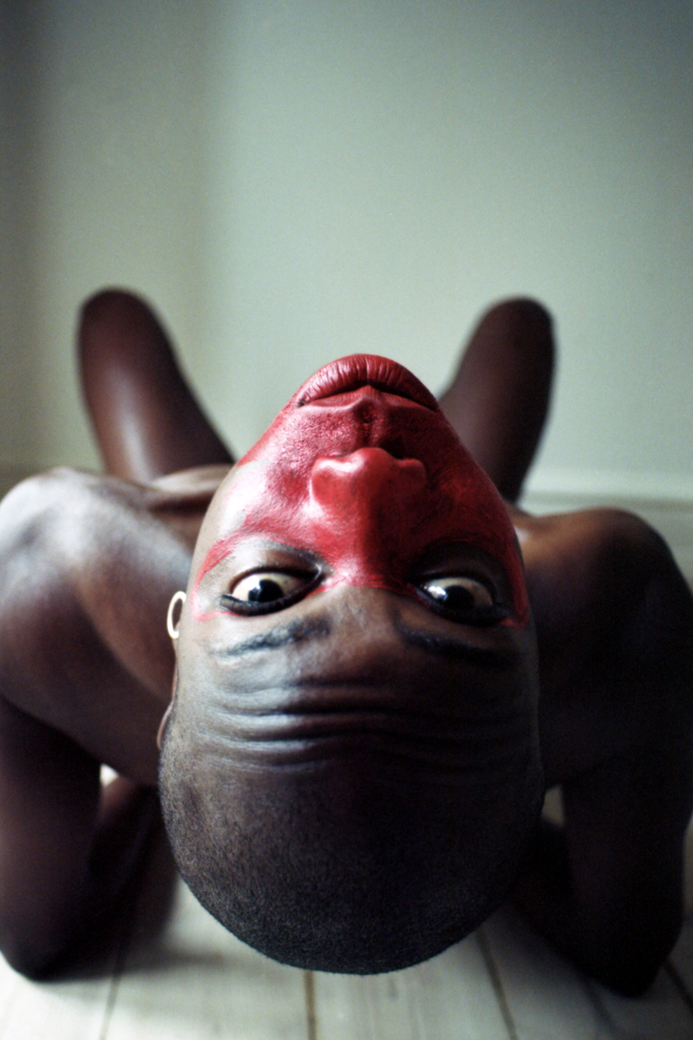 Annah Rita fotografat a testa in giù con tinta rossa in viso, progetto Show Me Your Queer