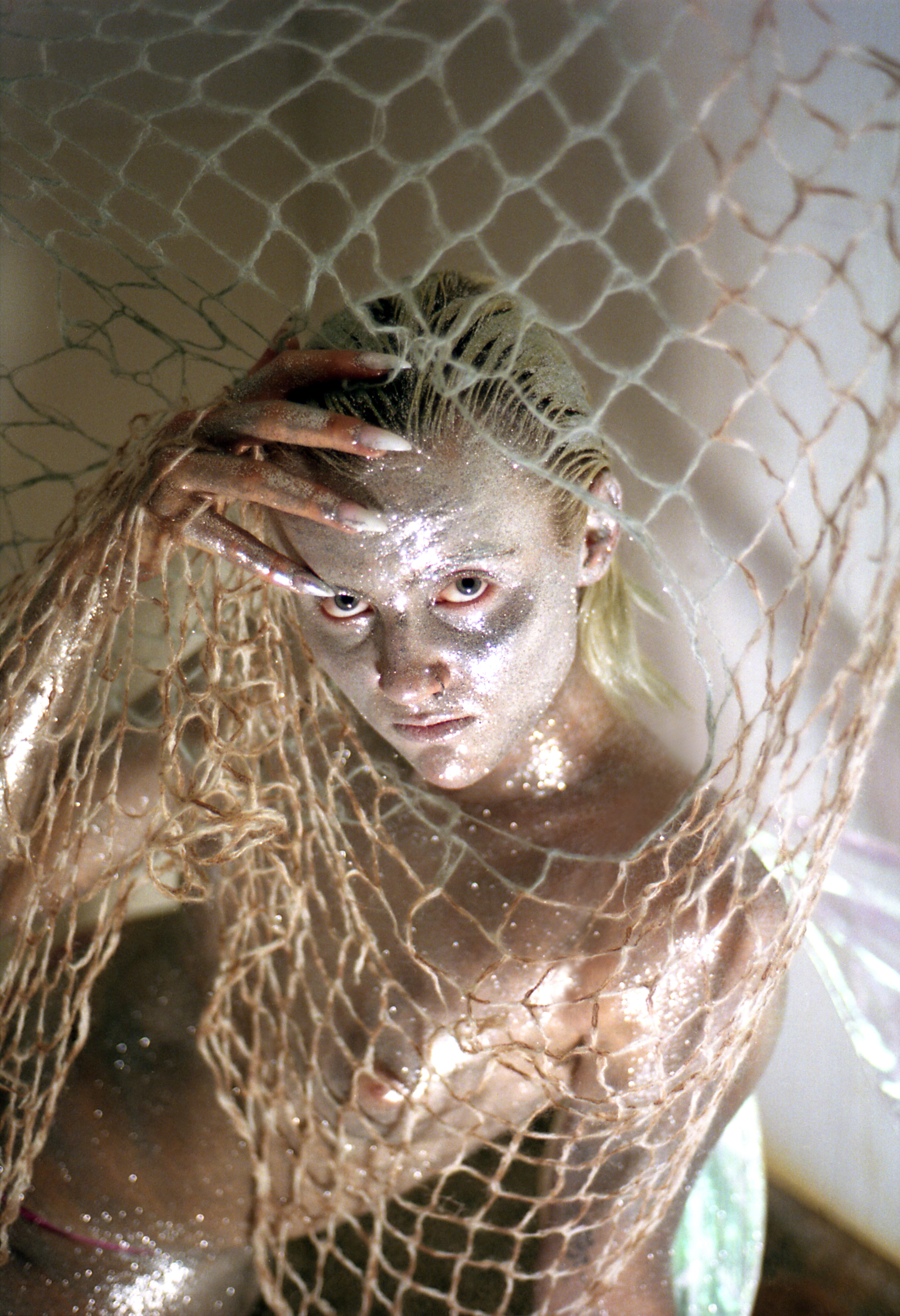 Aiko con corpo ricoperto di glitter argentati e una rete da pesca, progetto Show Me Your Queer