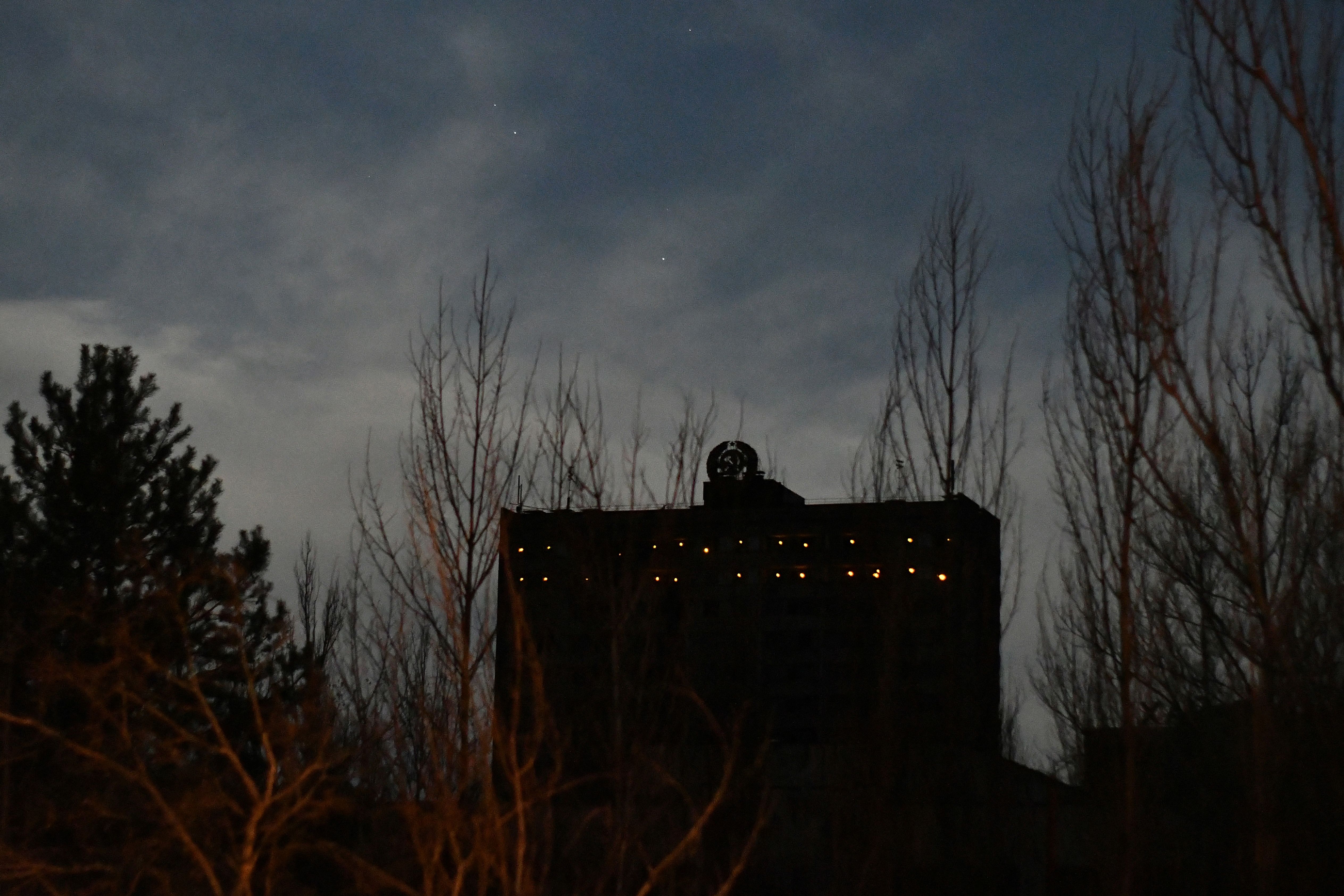 Cahaya lampu terpancar melalui jendela gedung terbengkalai di kota mati Pripyat. Foto: Genya Savilov/AFP