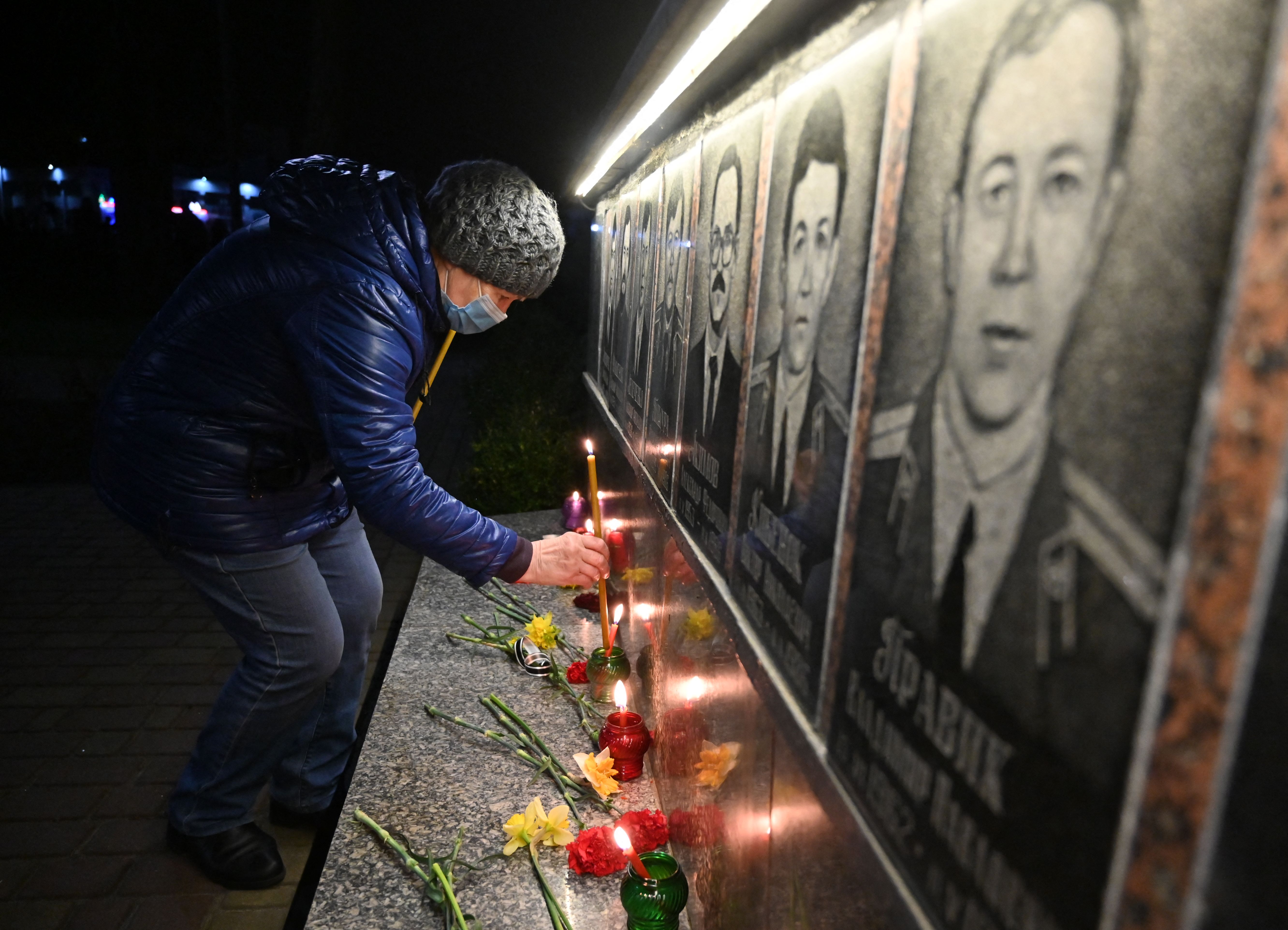 Perempuan menyalakan lilin dalam upacara peringatan yang diselenggarakan di Slavutych. Foto: Sergei Supinsky/AFP via Getty Images