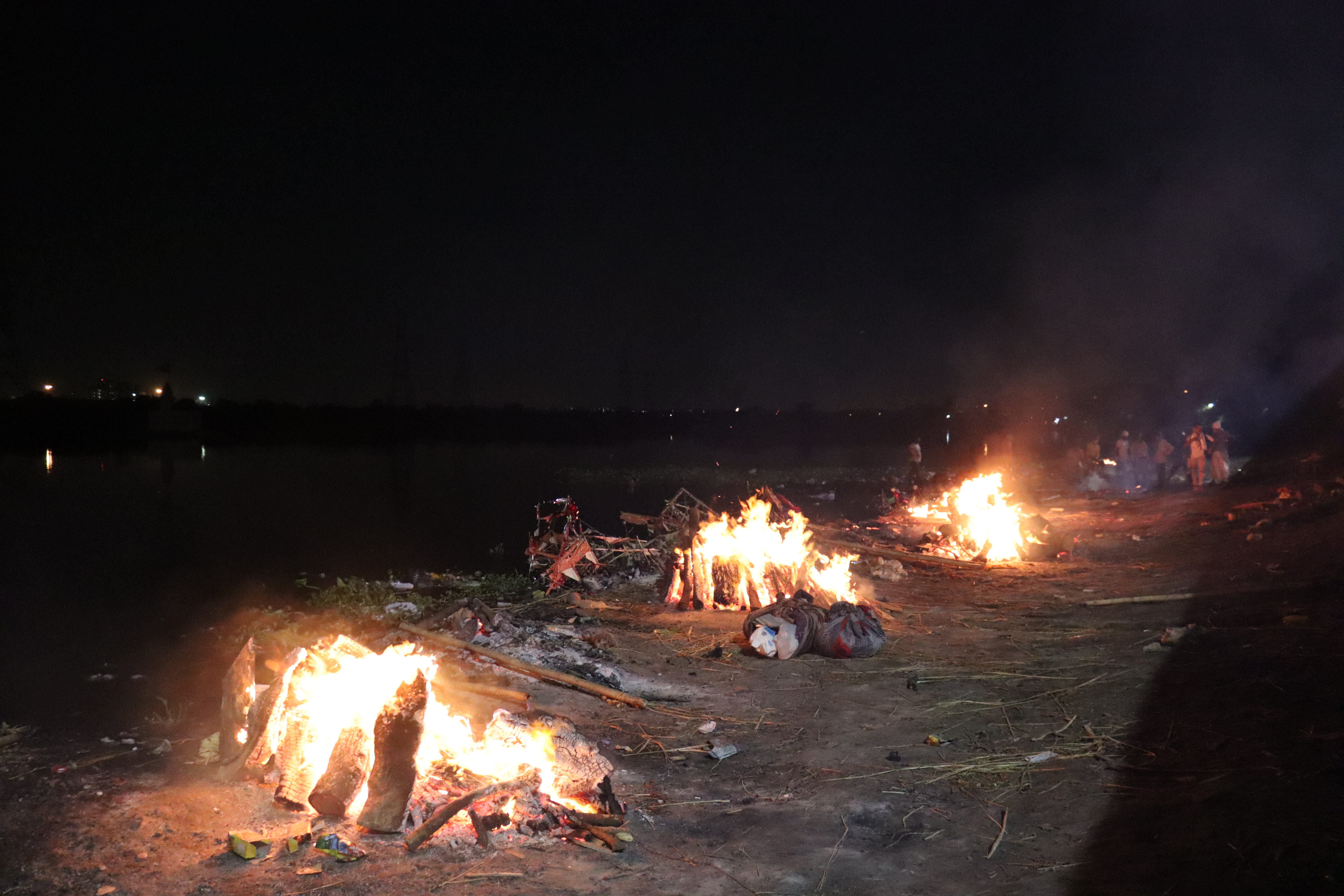 Tumpukan kayu yang membara di sepanjang tepi sungai Yamuna dekat krematorium Nigambodh Ghat pada 22 April 2021.
