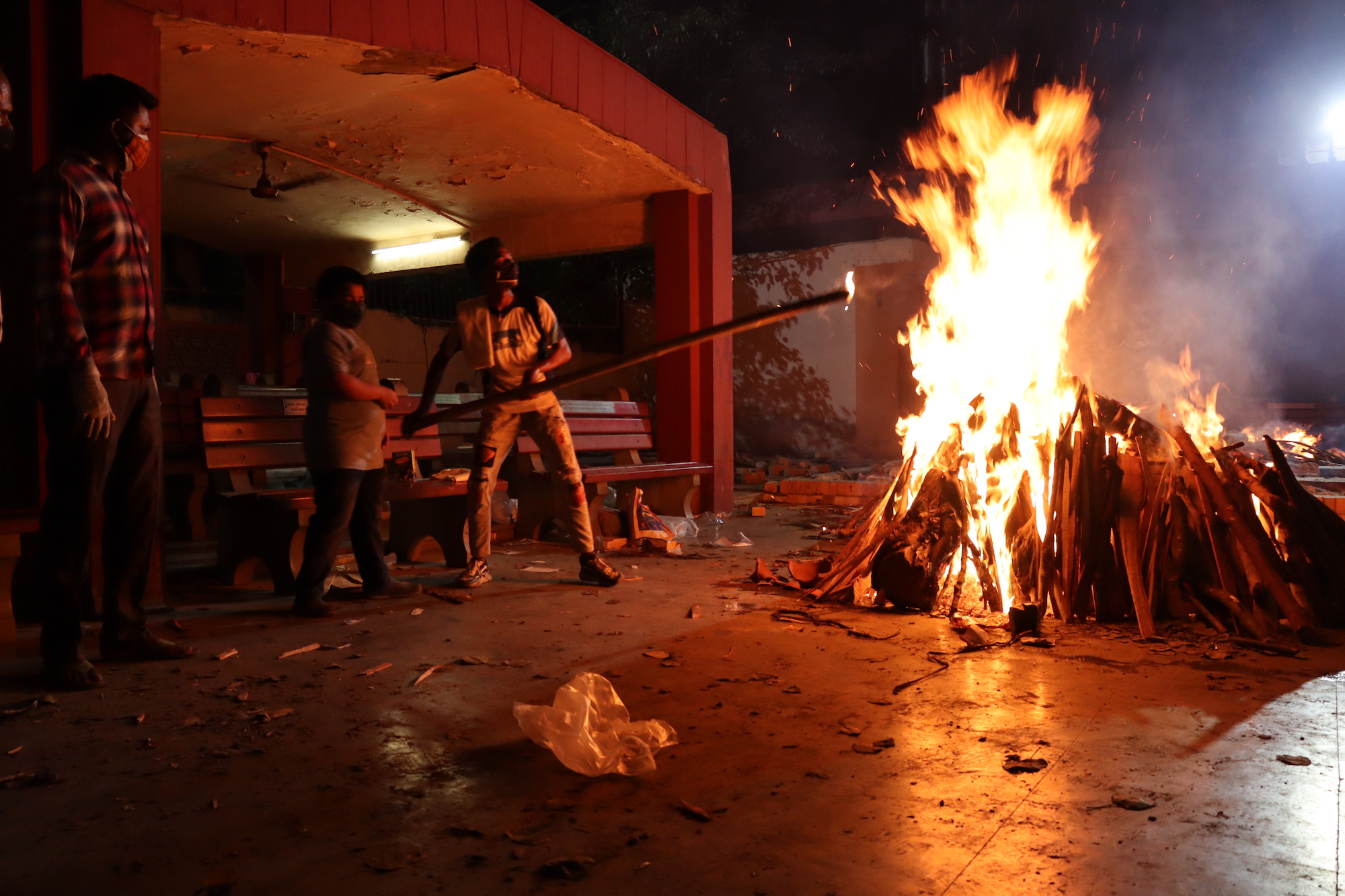 Ashu Rai membantu bocah 13 tahun Himanshu membakar tumpukan kayu kremasi.