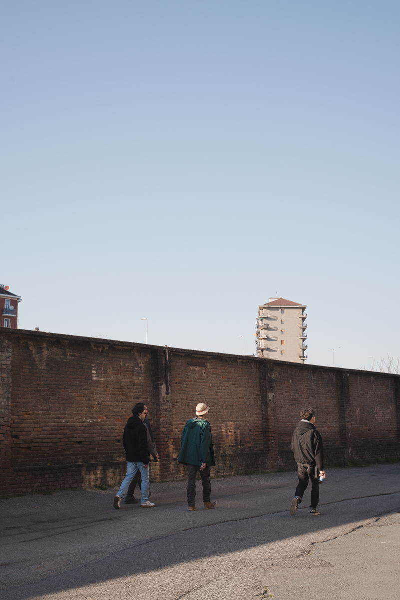 ragazzi che caminano davanti a un muro cielo azzurro, foto courtesy of Stasis