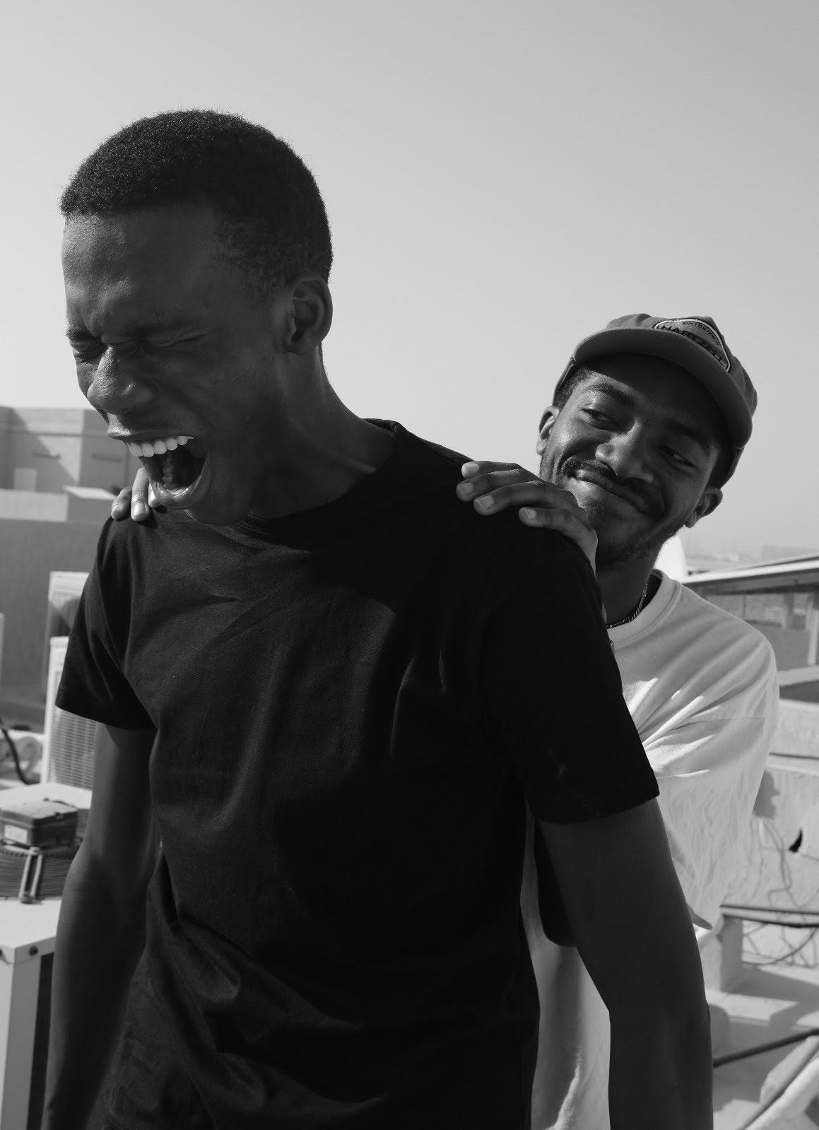a screaming man being held by his shoulders by a smiling friend behind him