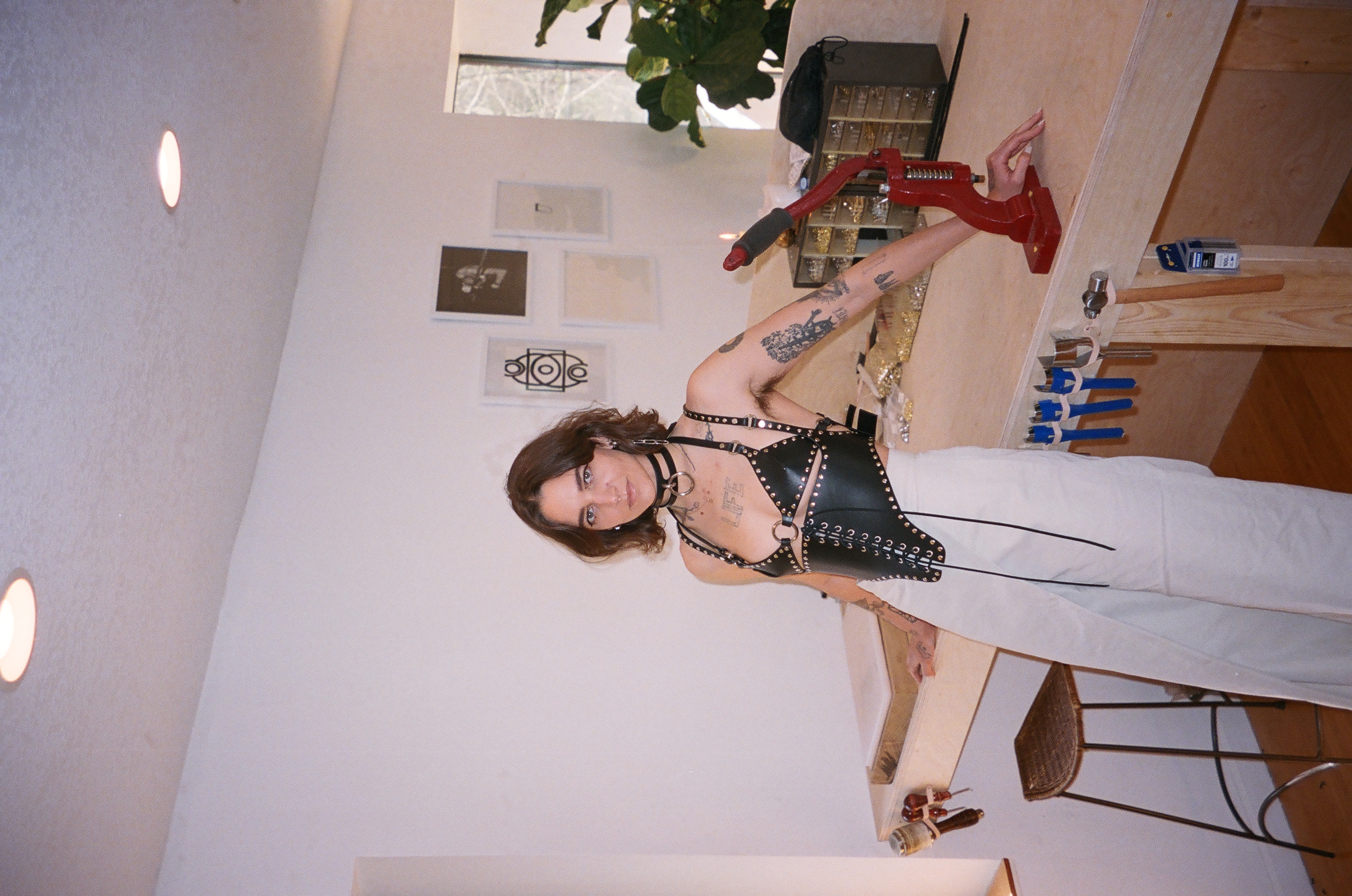 hunter savoy in a leather harness leaning against her work table