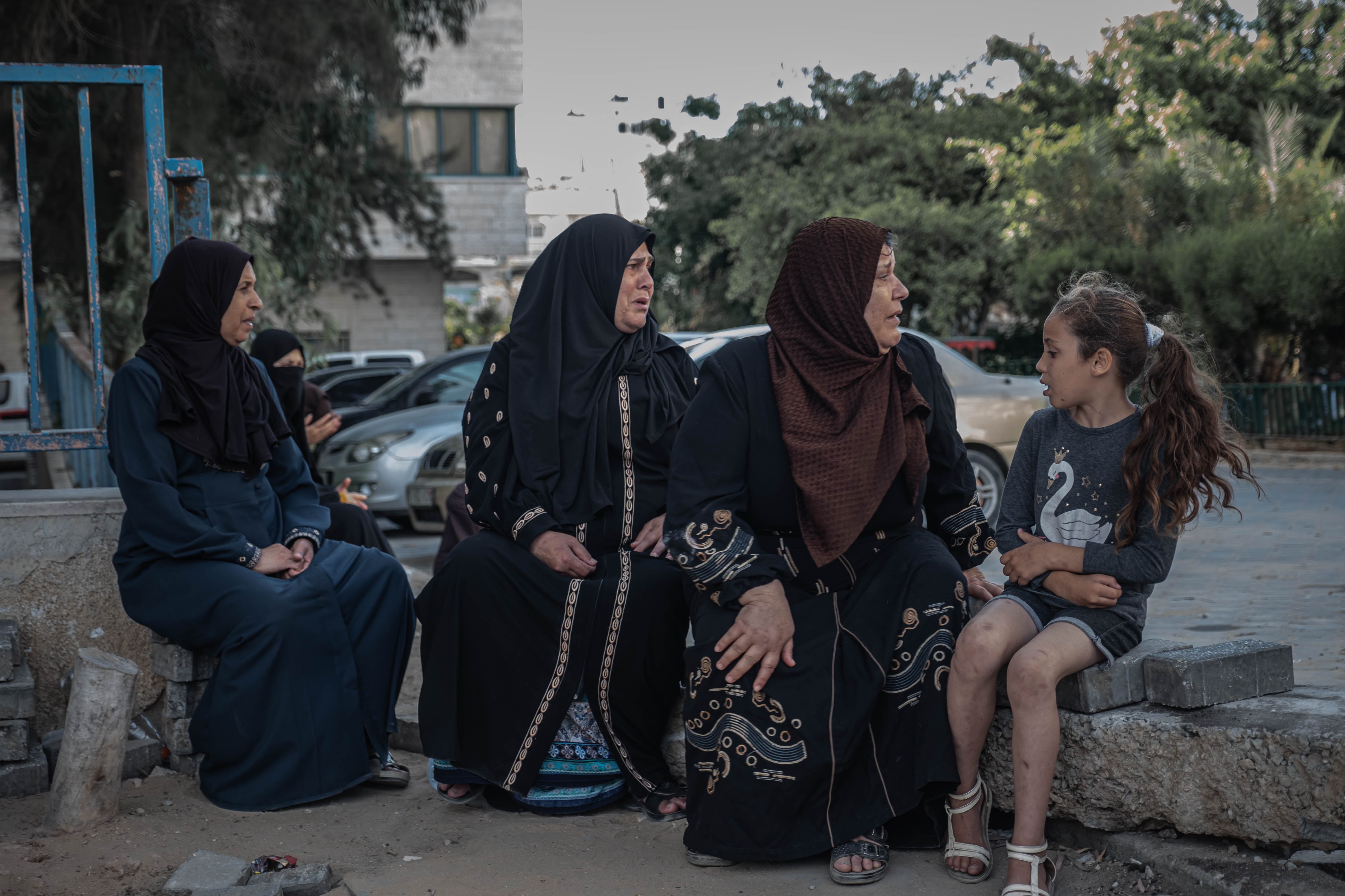 Beberapa perempuan di pinggiran Kota Gaza menanti kedatangan ambulans yang mengangkut jenazah keluarga mereka yang tewas akibat serangan Israel. Foto oleh Fatima Shbair/Getty Images
