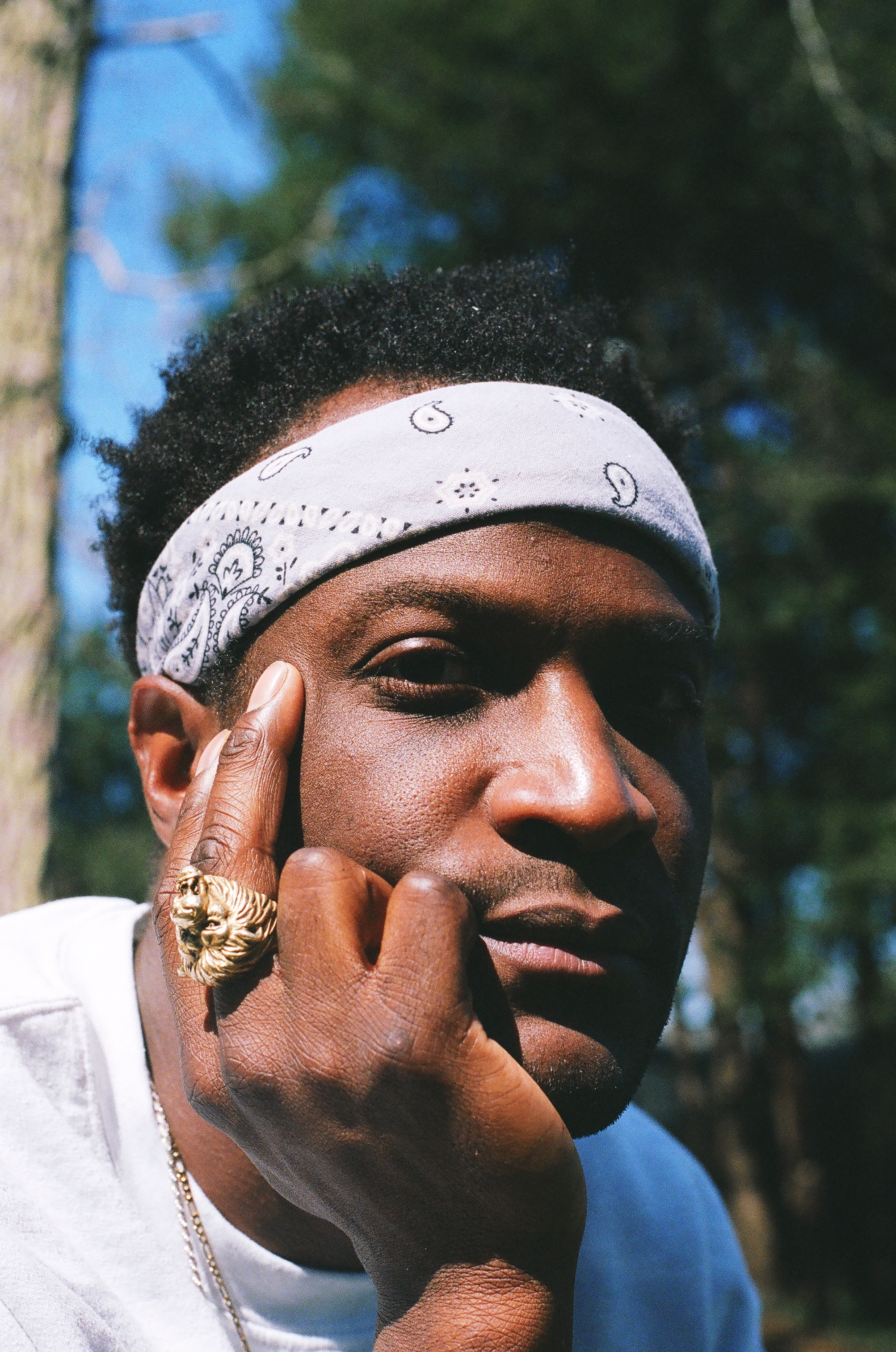 jaze uries profile wearing a gold ring and a white bandana
